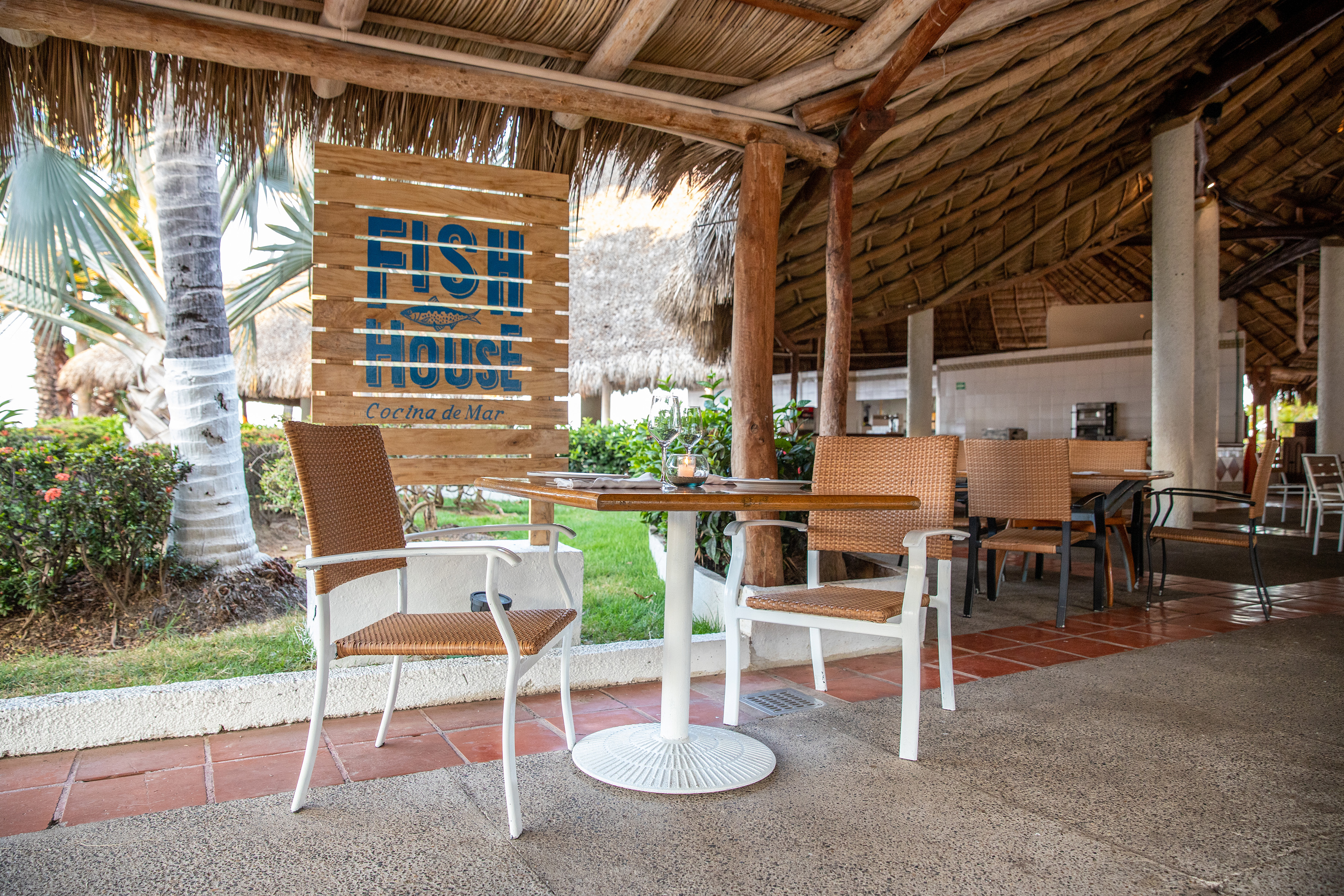 Fish House Cocina de Mar outdoor restaurant with thatched roof and dining tables.
