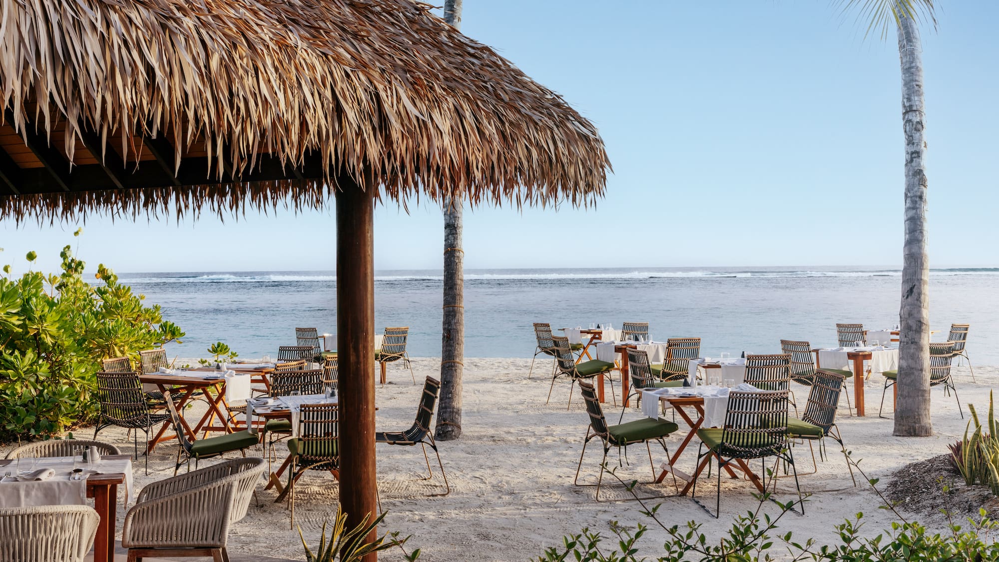 a beach with tables and chairs and a hut