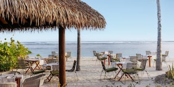 a beach with tables and chairs and a hut