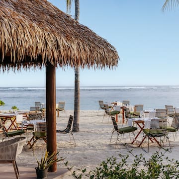 a beach with tables and chairs and a hut