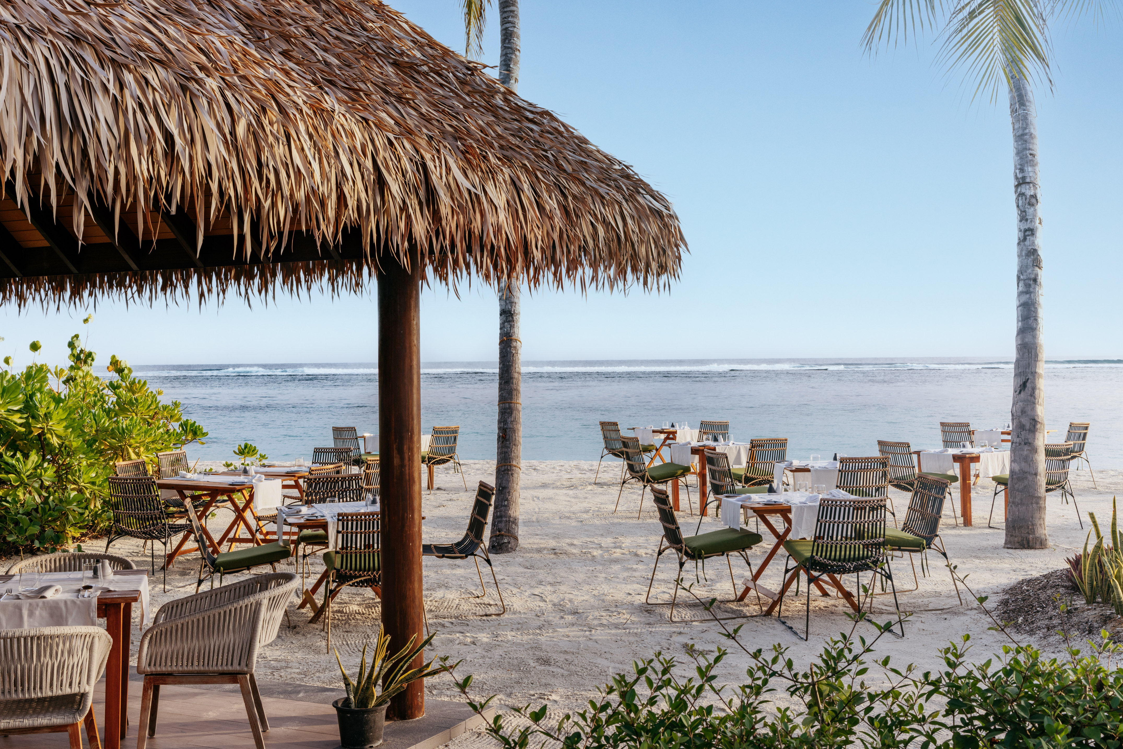 a beach with tables and chairs and a hut
