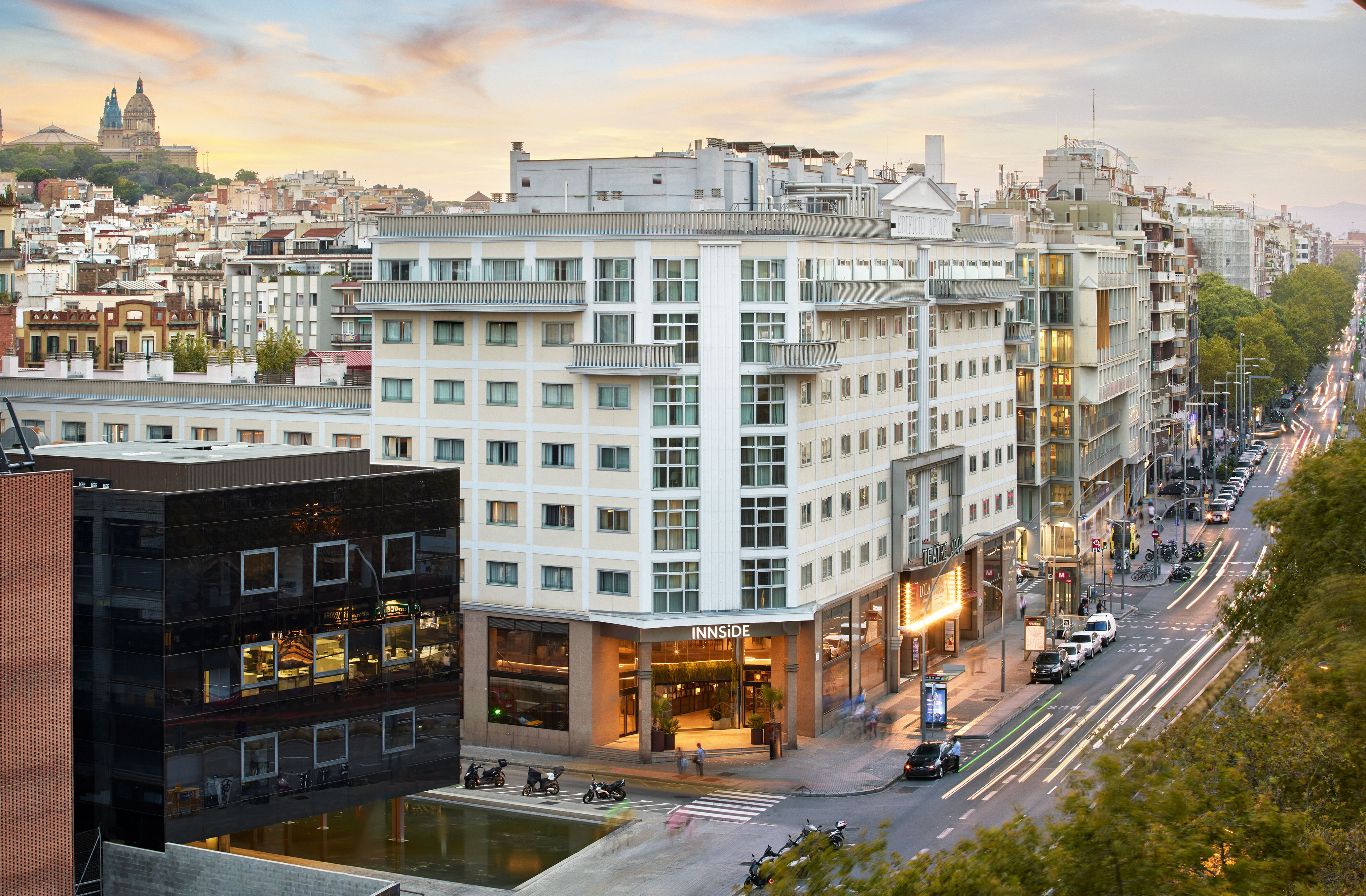 Innside hotel building in Barcelona at dusk, urban street scene with car trails.