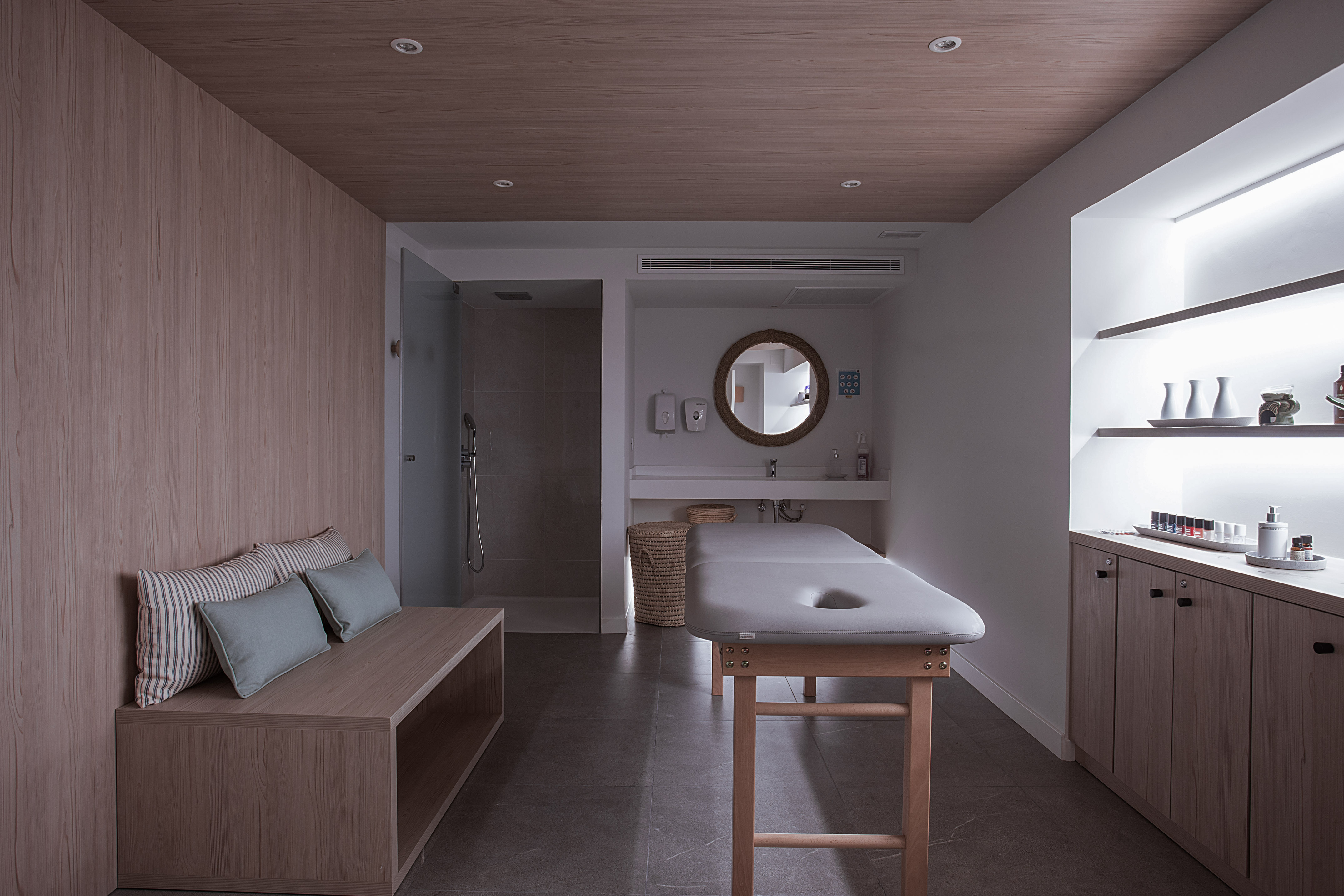 Serene spa therapy room with massage table, wood details, and shower.