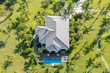 a house with a pool surrounded by palm trees