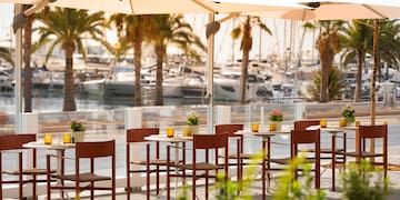 a table and chairs outside with boats in the background