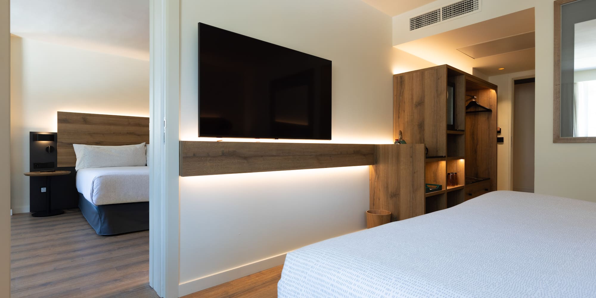 Modern hotel suite with flat-screen TV and adjoining bedroom.