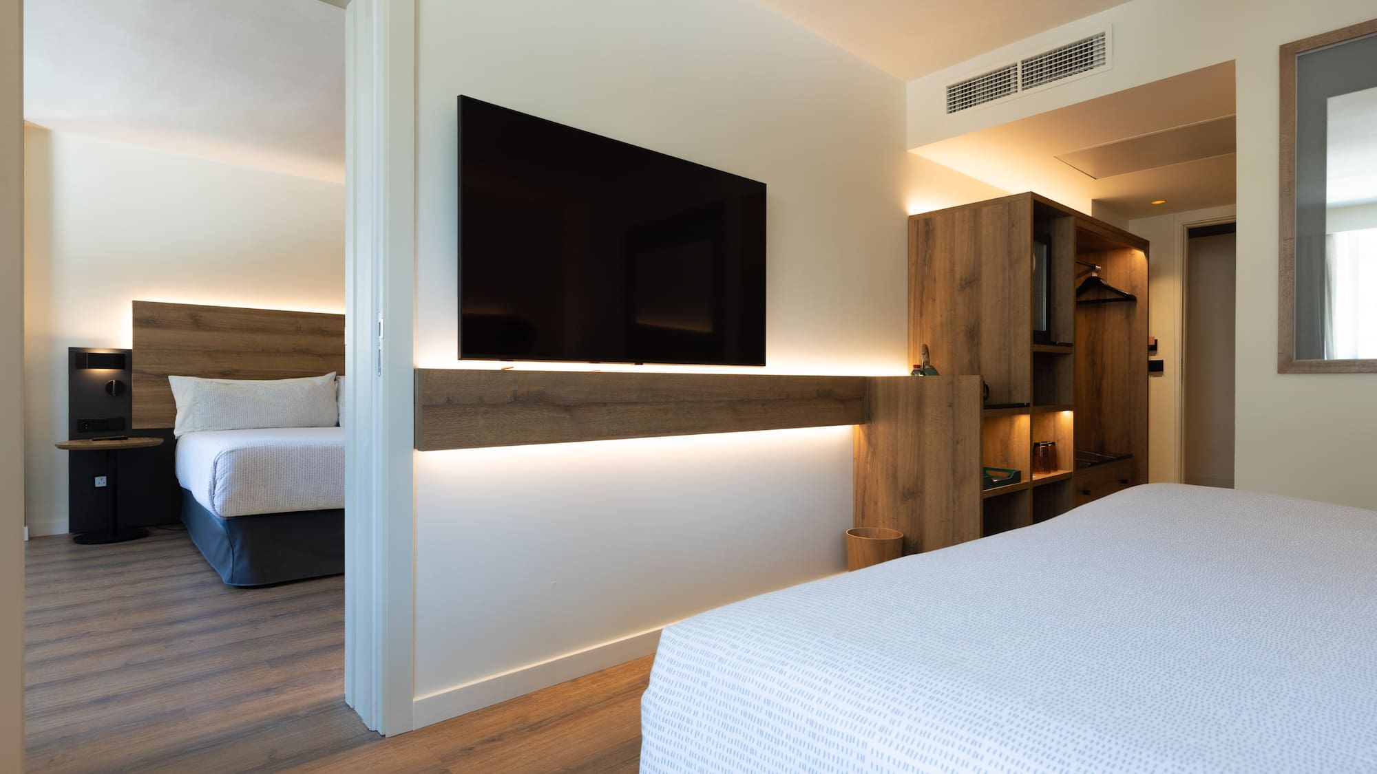 Modern hotel suite with flat-screen TV and adjoining bedroom.