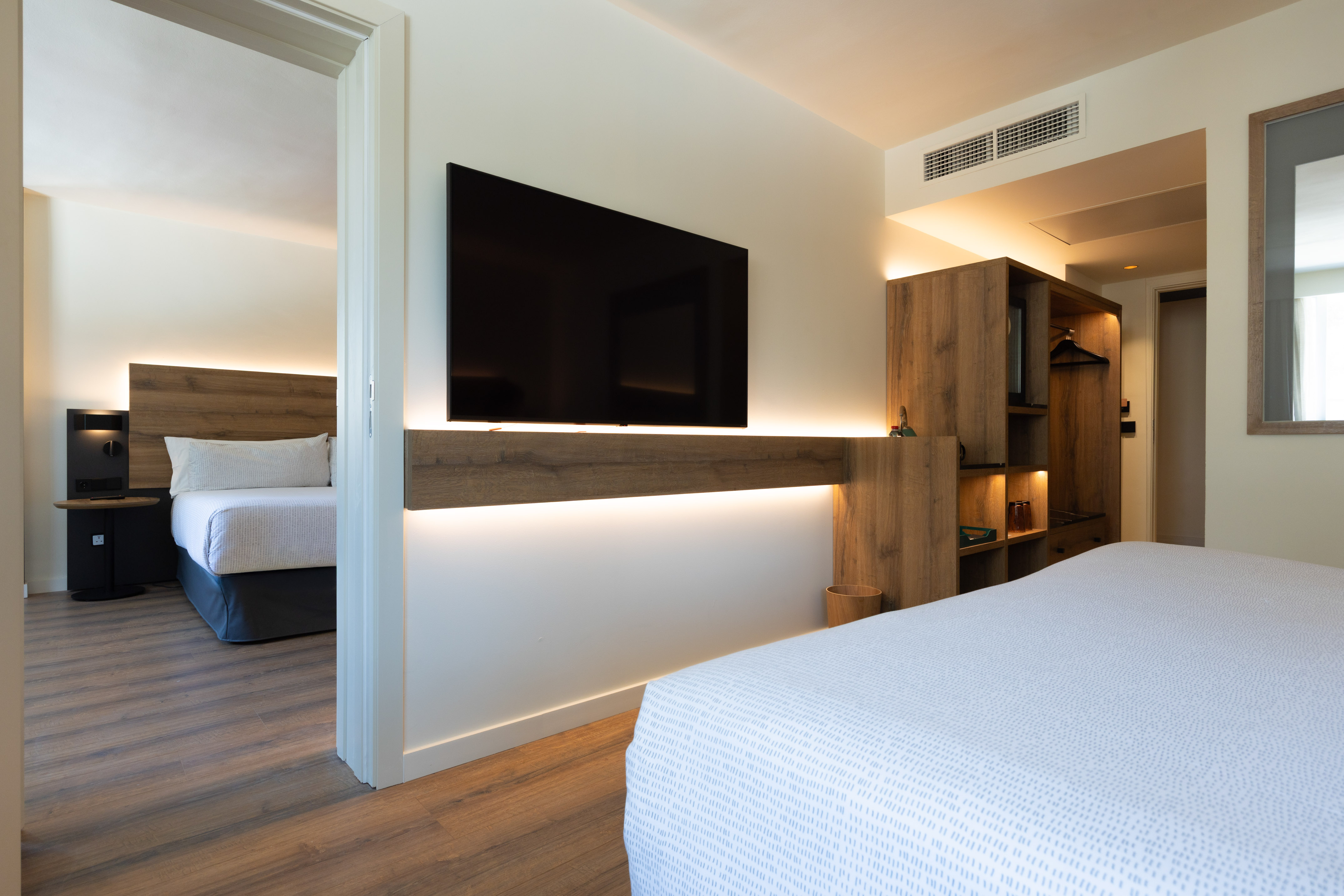 Modern hotel suite with flat-screen TV and adjoining bedroom.
