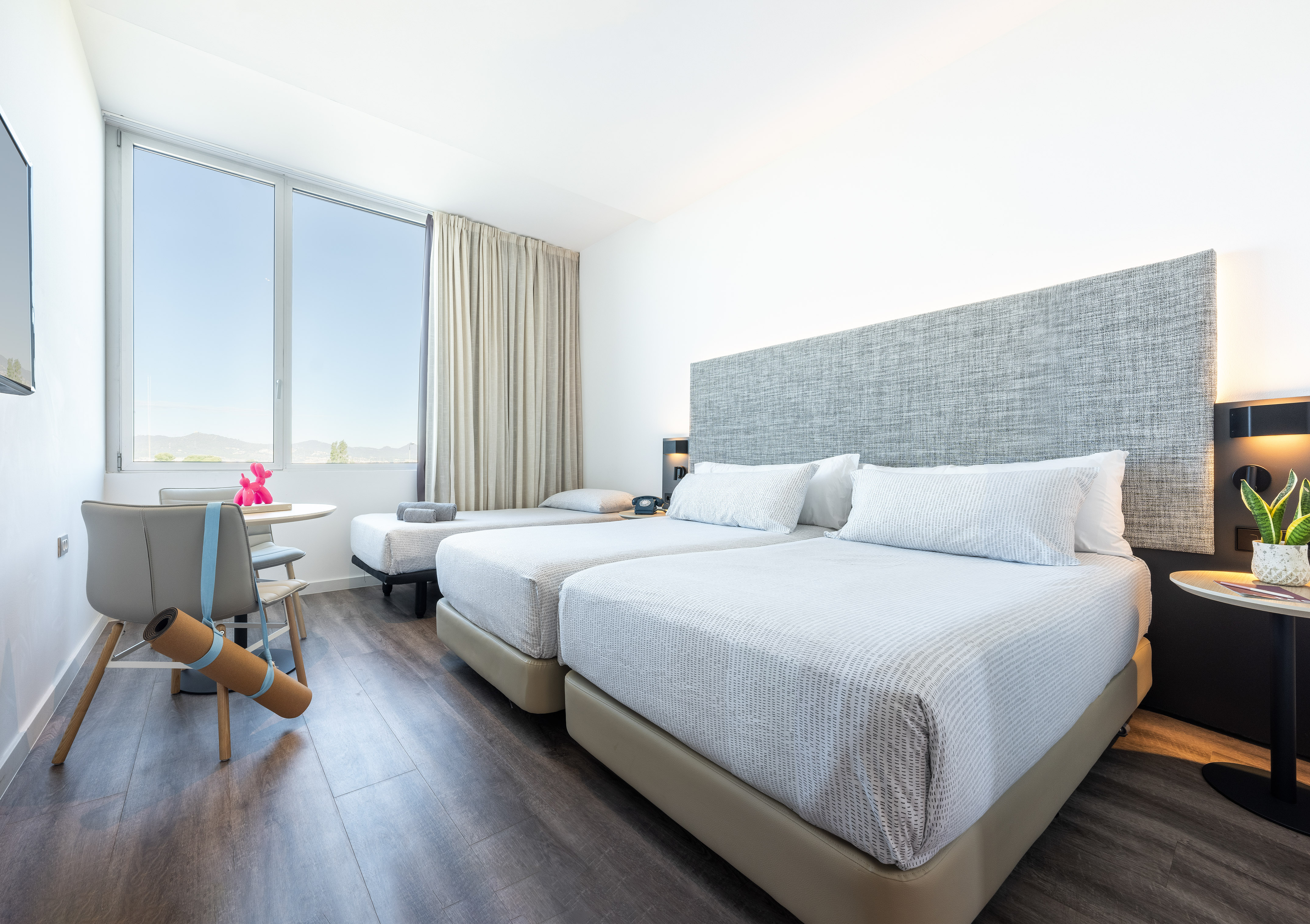 Hotel triple room with twin beds, window mountain view, and yoga mat.