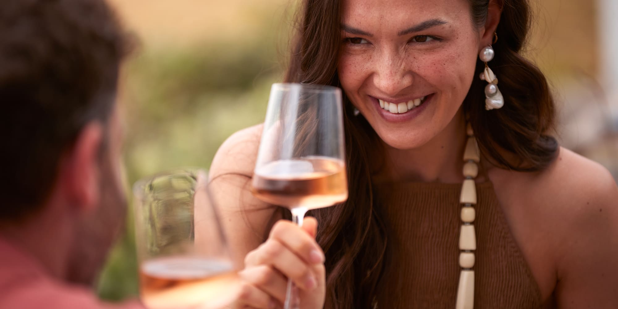 a woman holding a wine glass with a man in the background