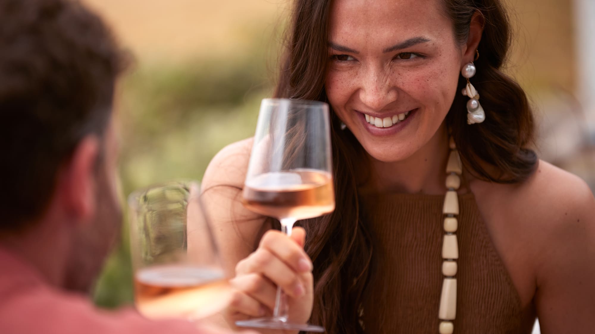a woman holding a wine glass with a man in the background
