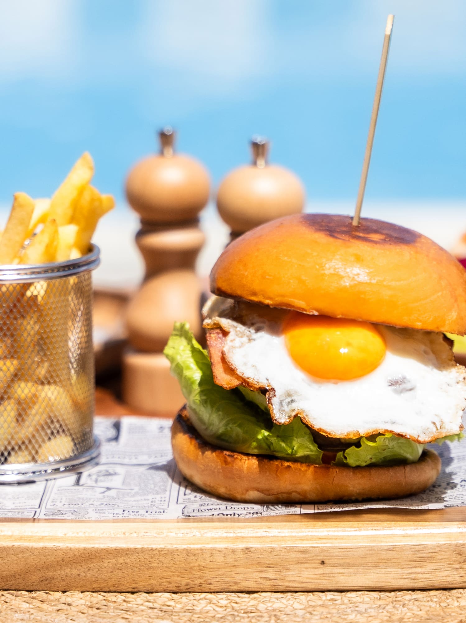 a burger with a egg on it and fries on a tray