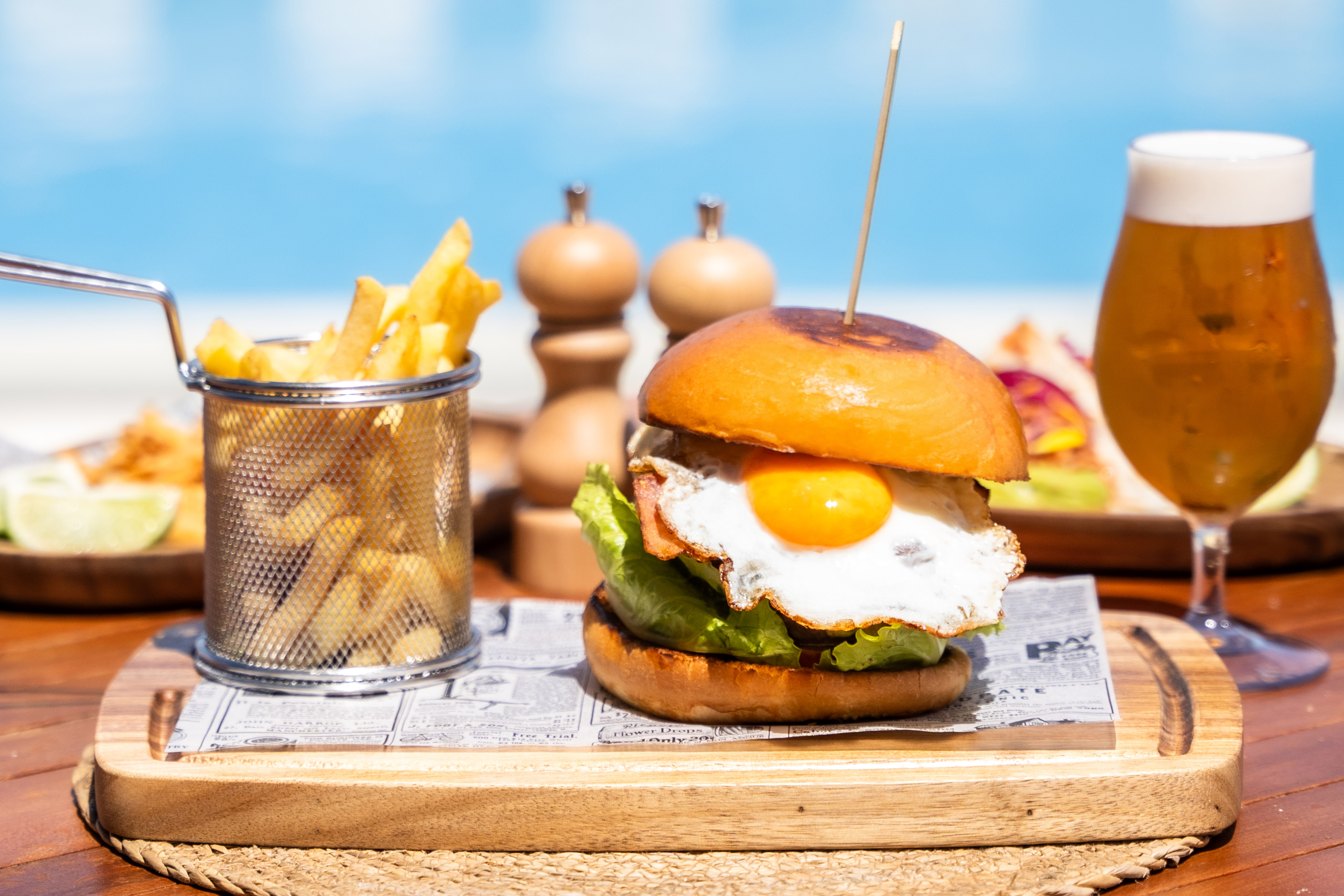 a burger with a egg on it and fries on a tray