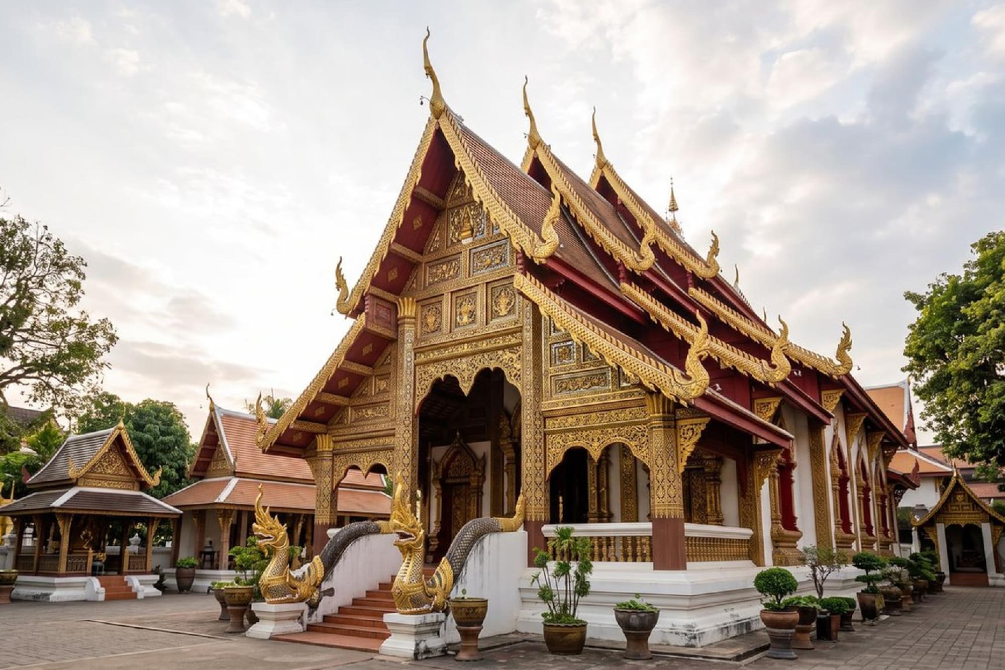 Traditional Thai temple with golden facade, red roofs, and Naga statues.