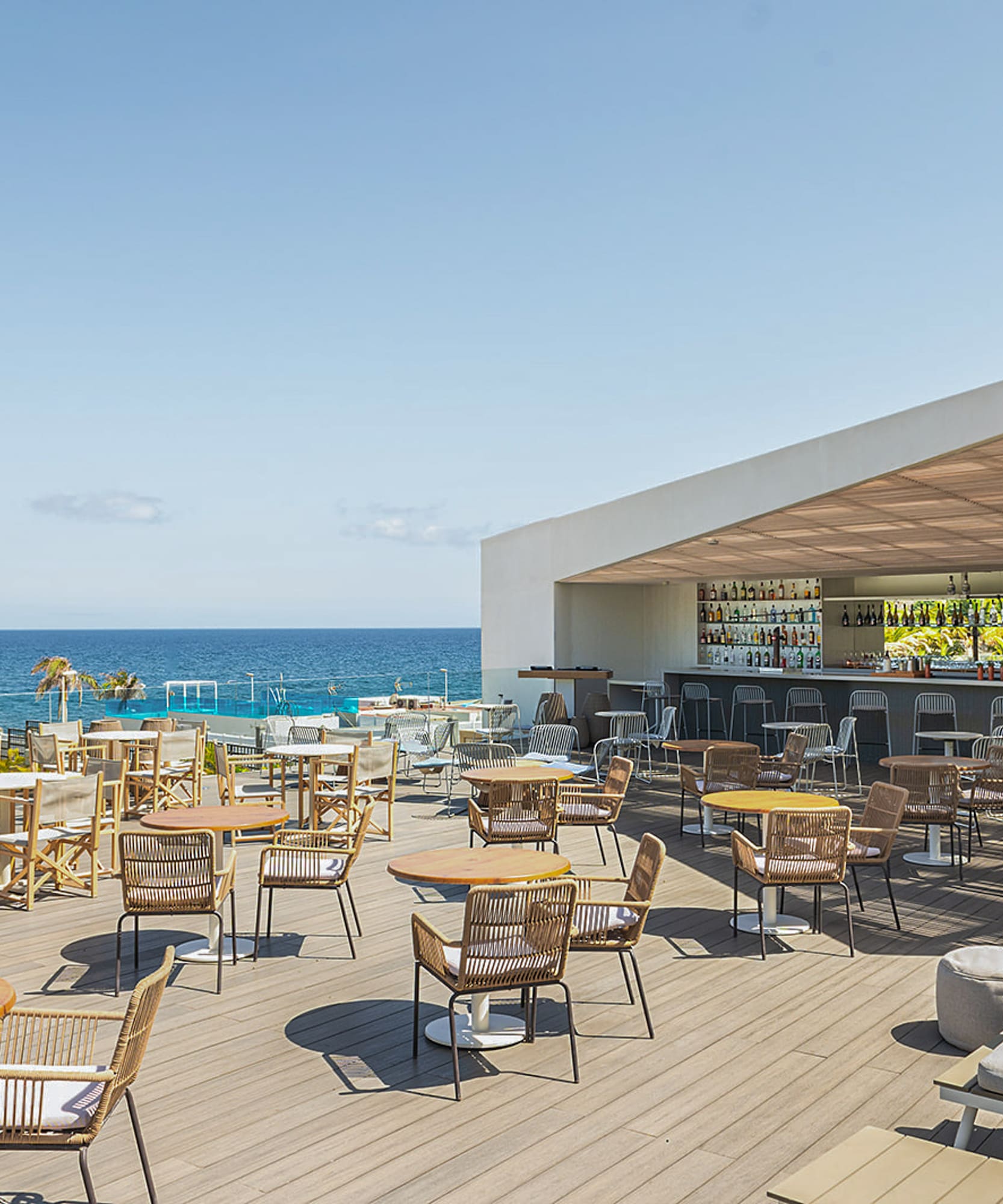 a patio with tables and chairs on a deck overlooking the ocean