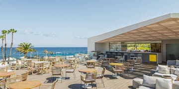 a patio with tables and chairs on a deck overlooking the ocean