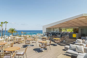 a patio with tables and chairs on a deck overlooking the ocean