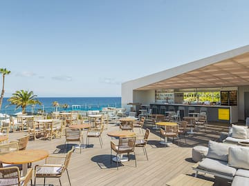 a patio with tables and chairs on a deck overlooking the ocean