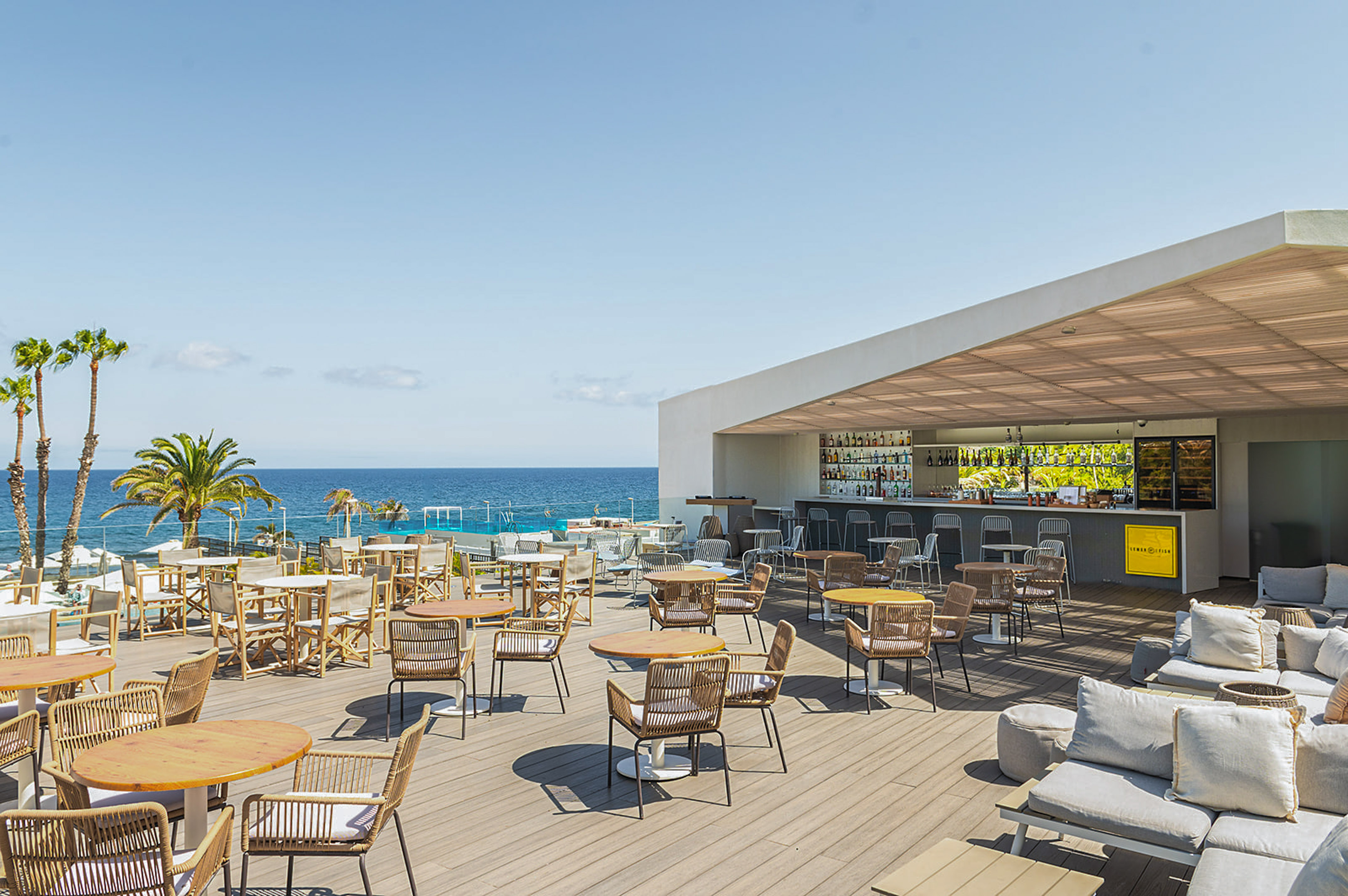 a patio with tables and chairs on a deck overlooking the ocean