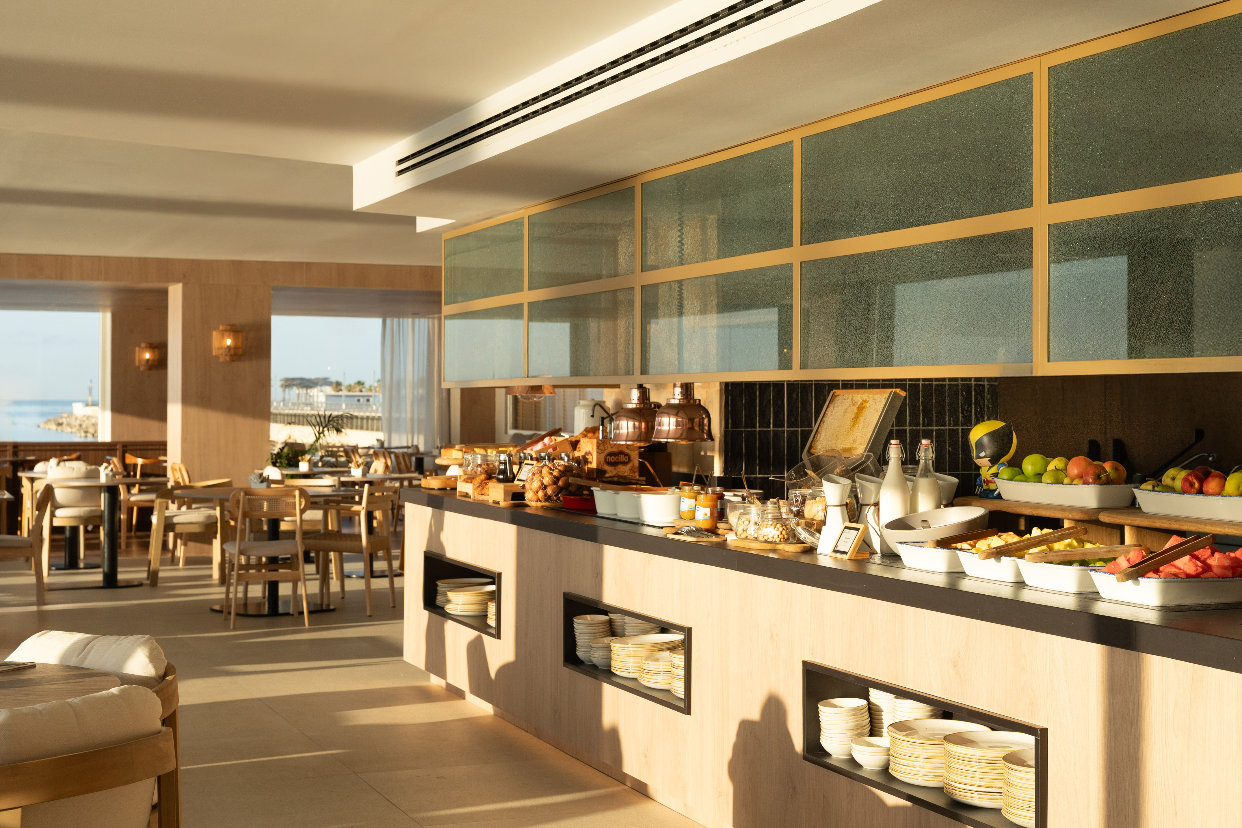 Modern breakfast buffet in a bright hotel restaurant overlooking the ocean.