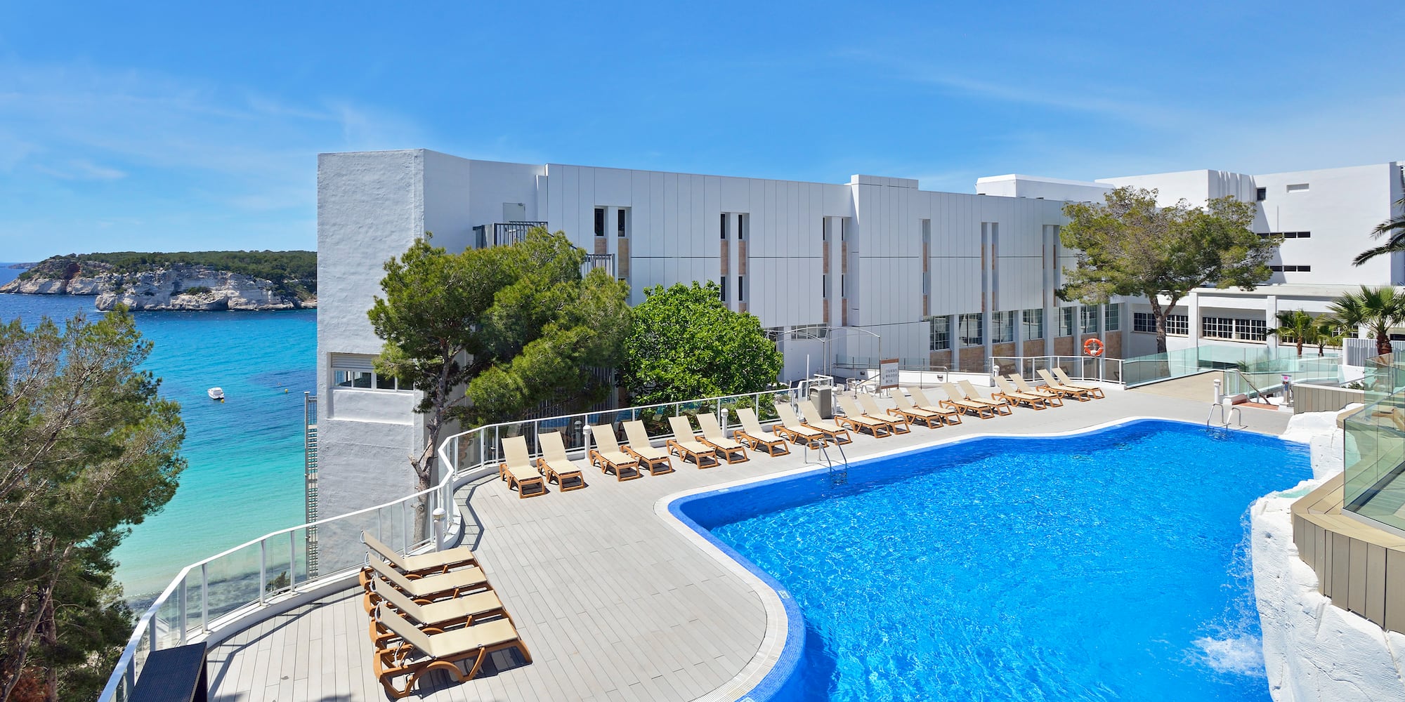 a pool with chairs and a building in the background