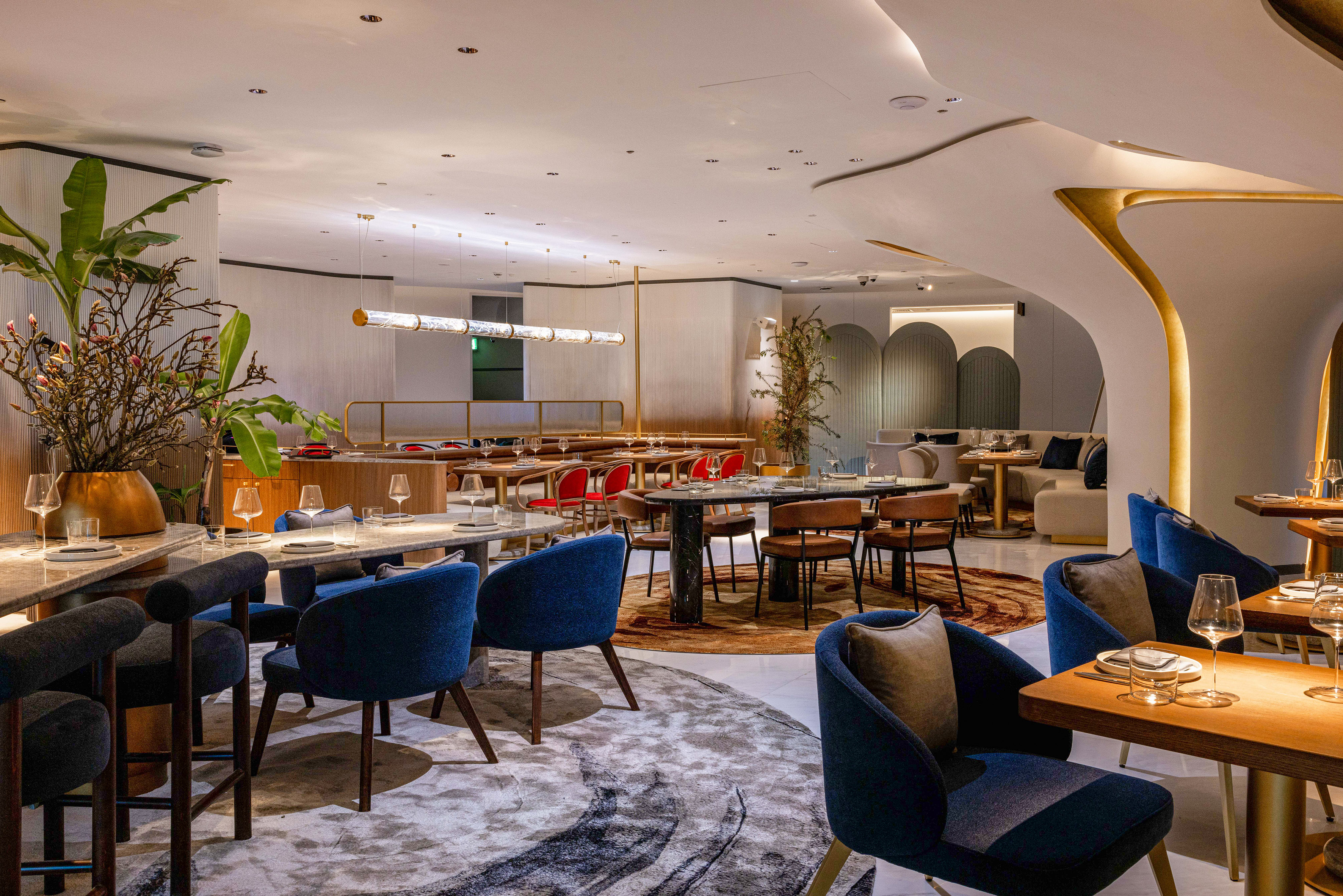 Upscale restaurant dining room with blue chairs, modern decor, and elegant lighting.