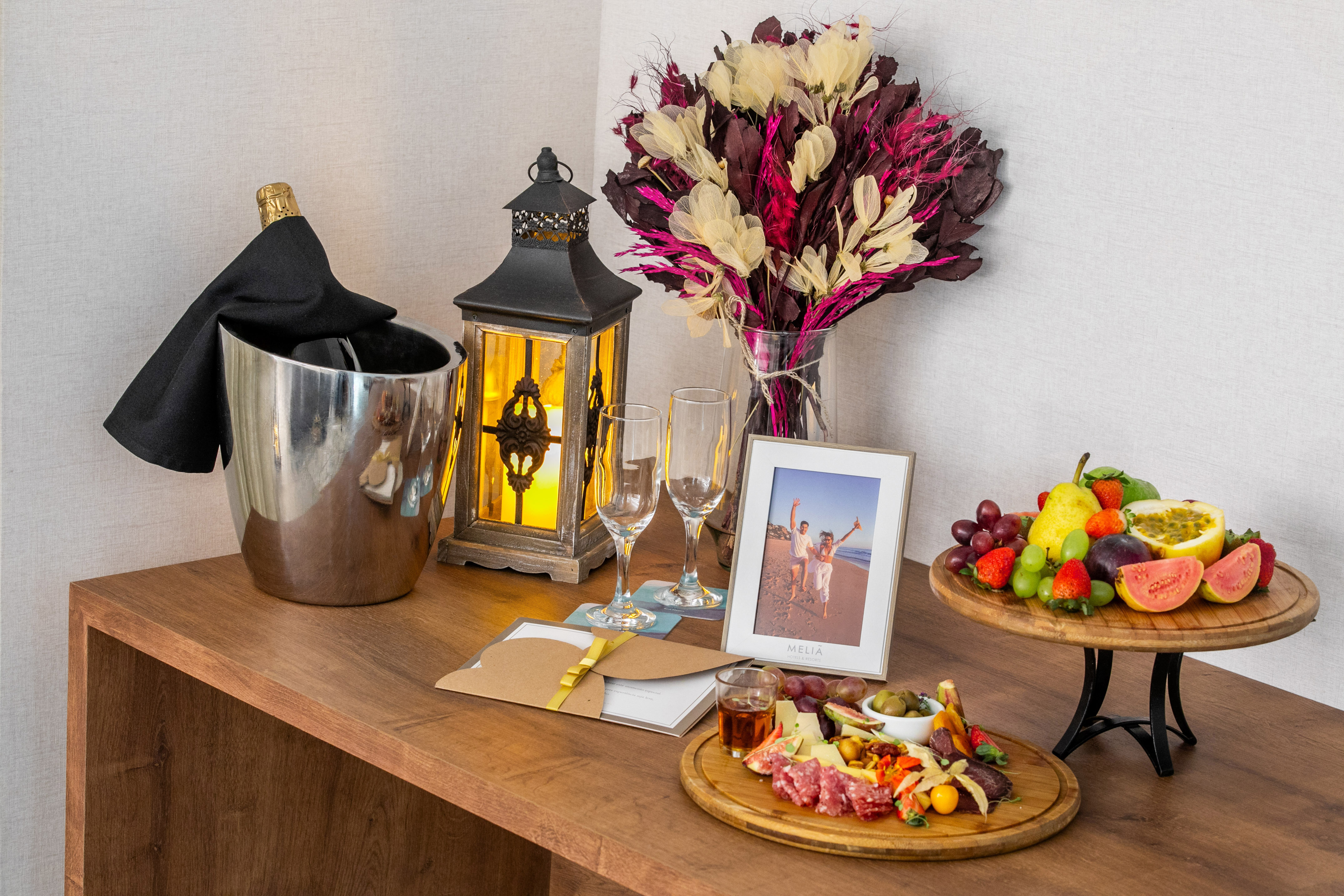 Hotel welcome amenity: champagne, charcuterie, fruit, lantern, framed photo.