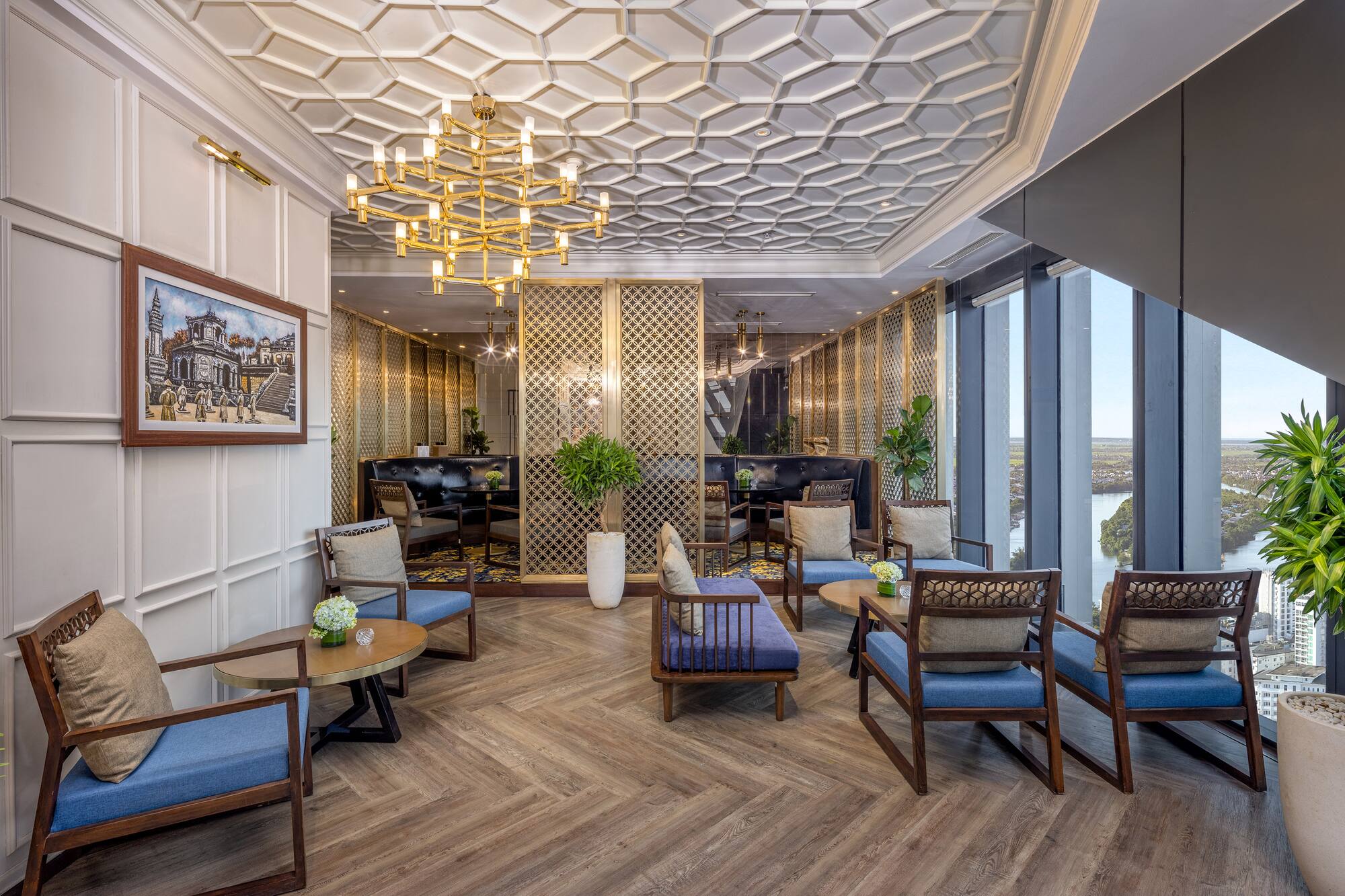Modern luxury lounge with golden chandelier, geometric ceiling, and city views.