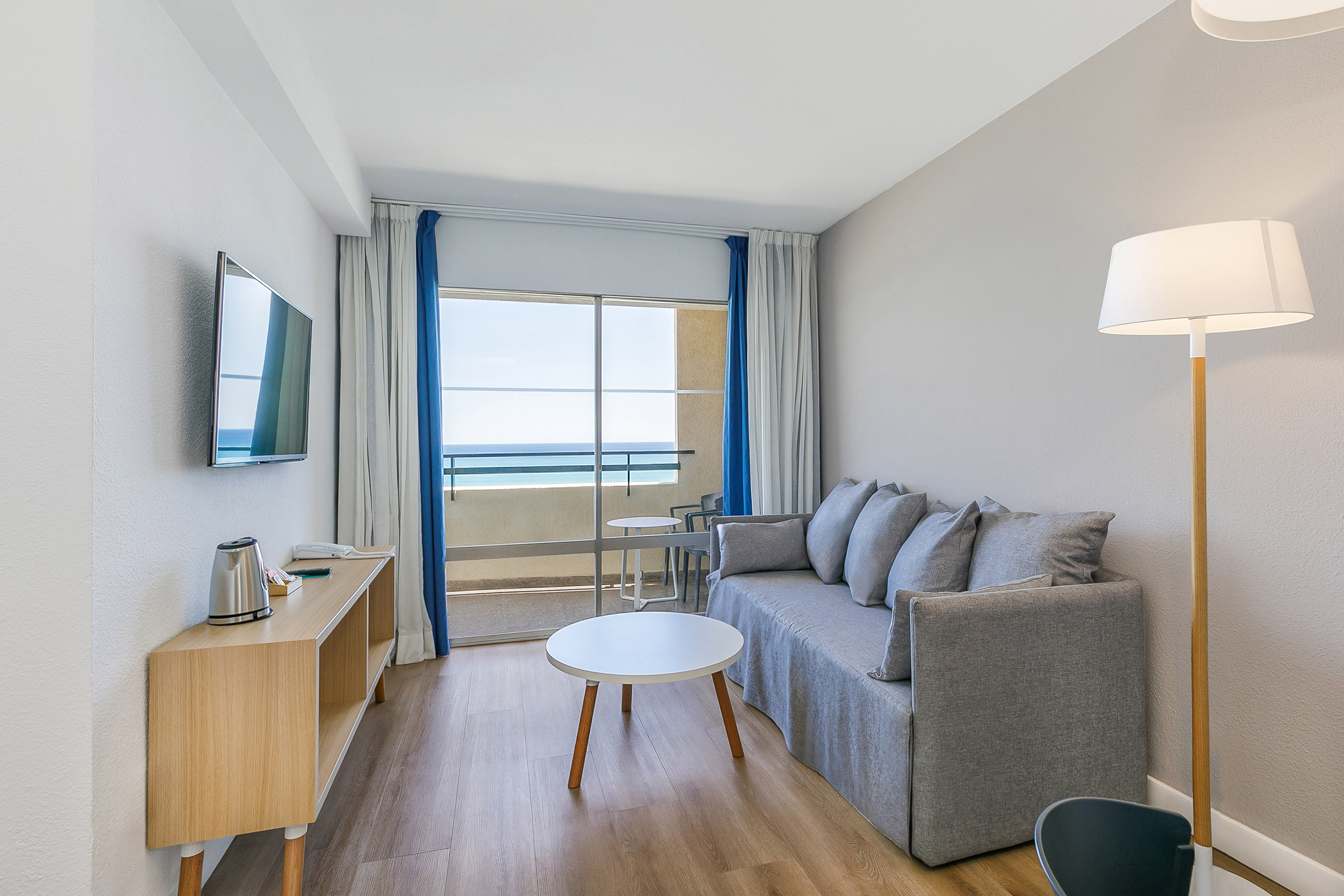 Hotel apartment living room with ocean view, sofa, and modern decor.