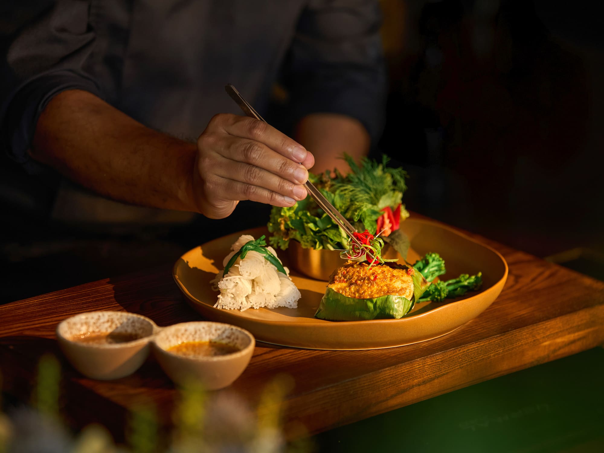 a person holding a pair of tongs over a plate of food