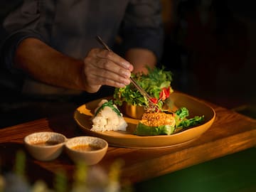 a person holding a pair of tongs over a plate of food