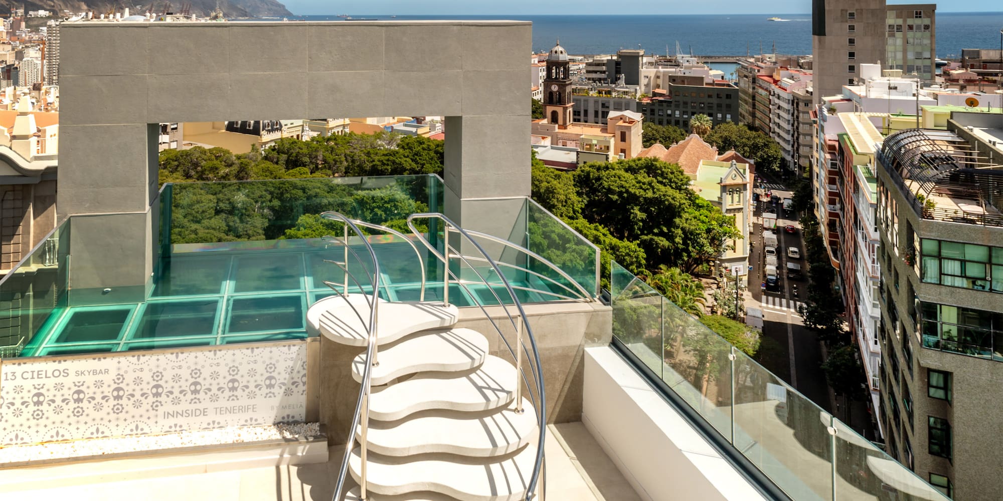 a rooftop with a glass railing and a city view