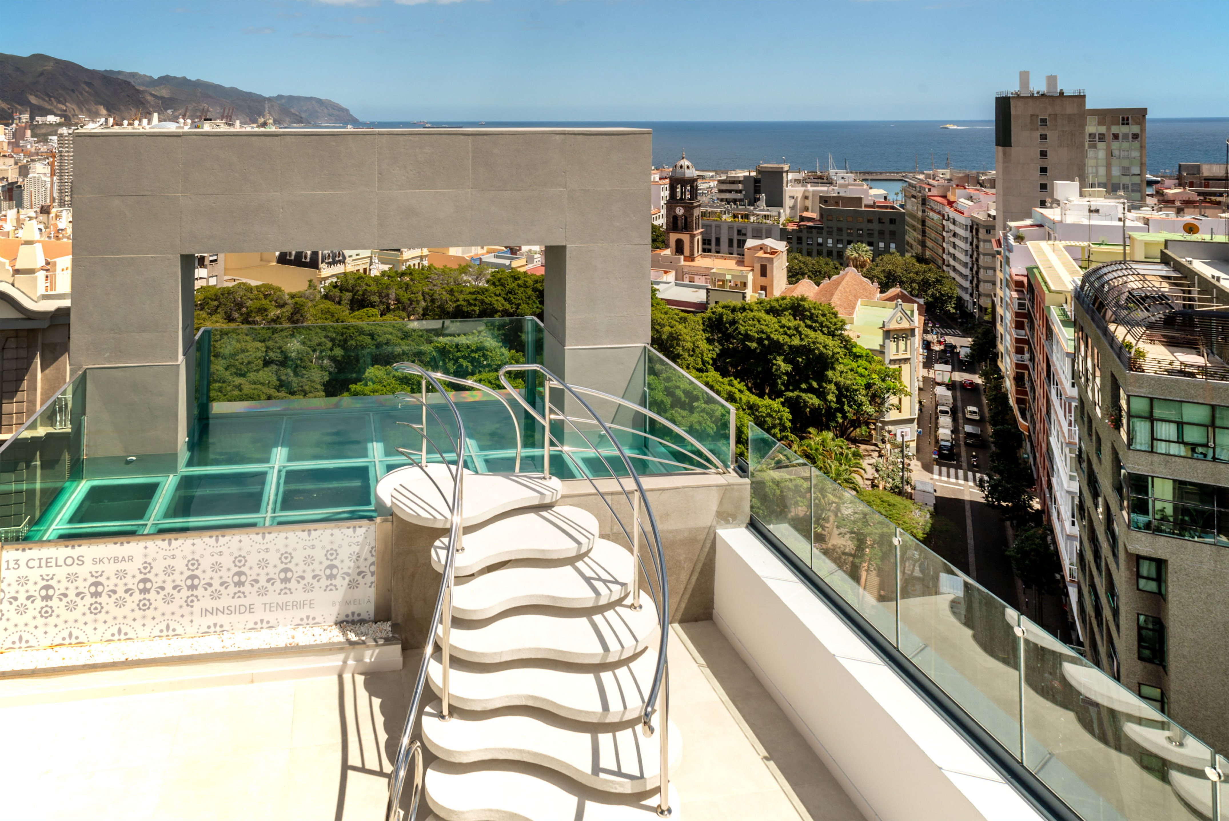 Tenerife skybar rooftop: wavy stairs, glass floor, city, and ocean view.