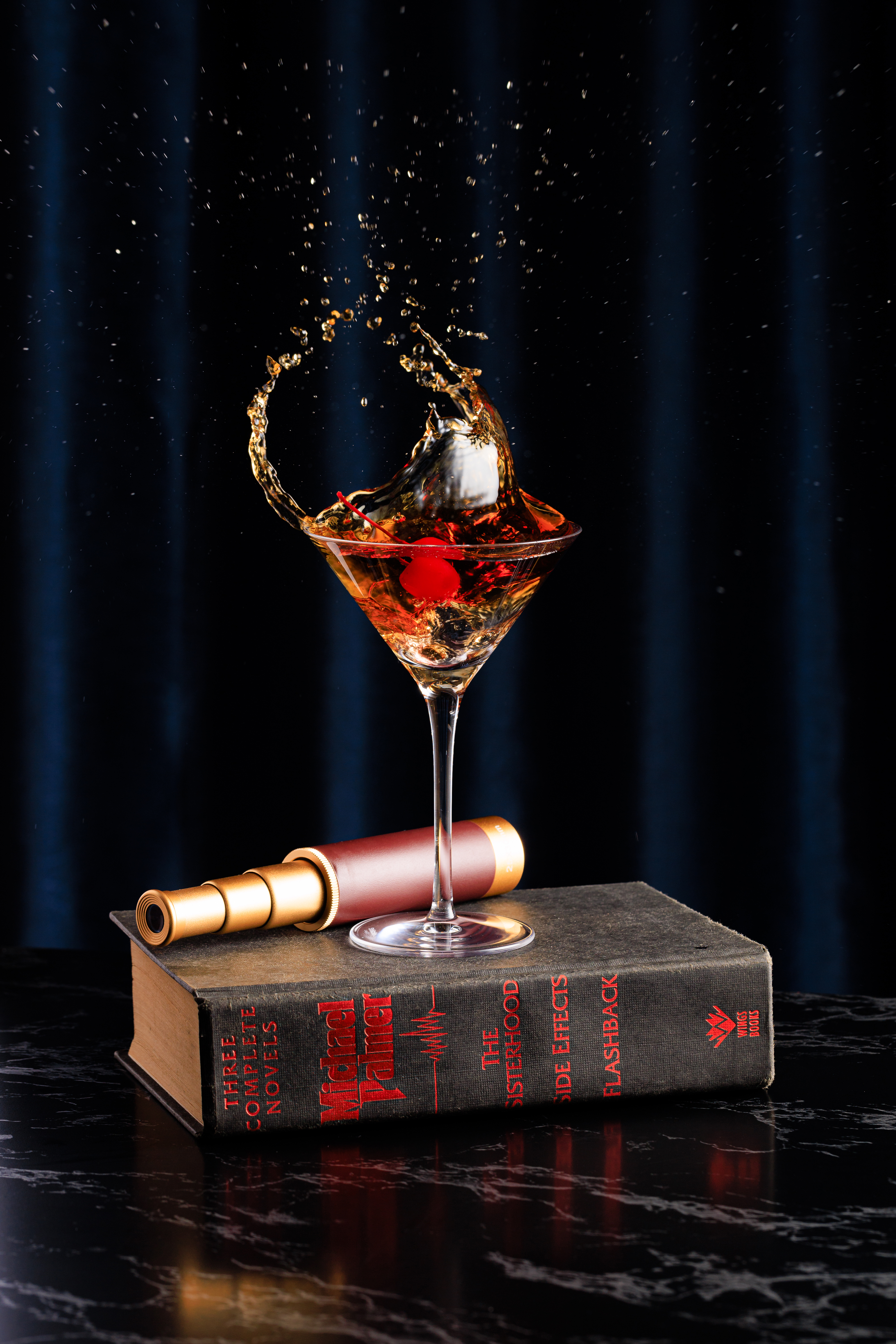 a glass of liquid with a cherry splashing out of it