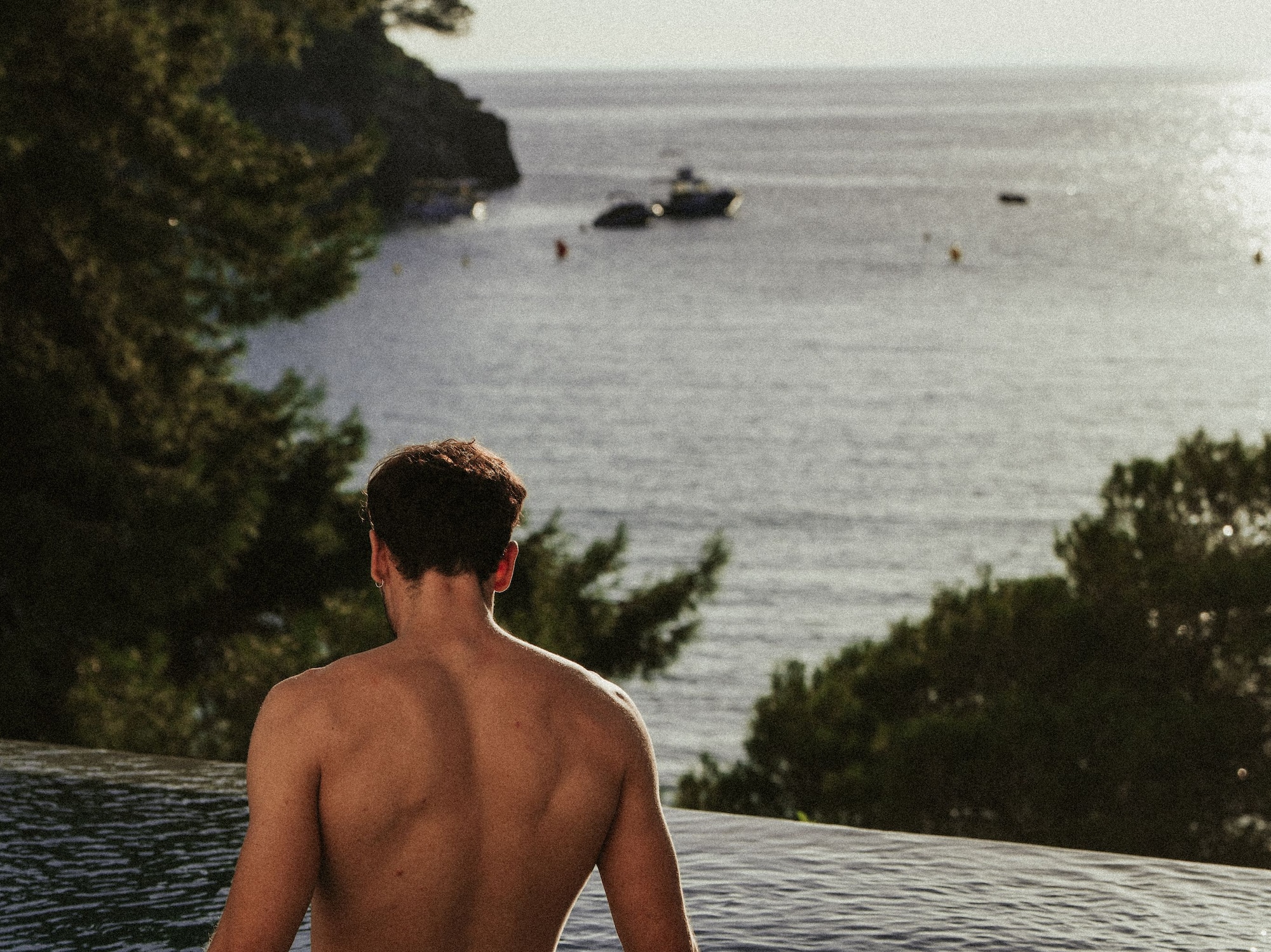 a man sitting in a pool looking out over water