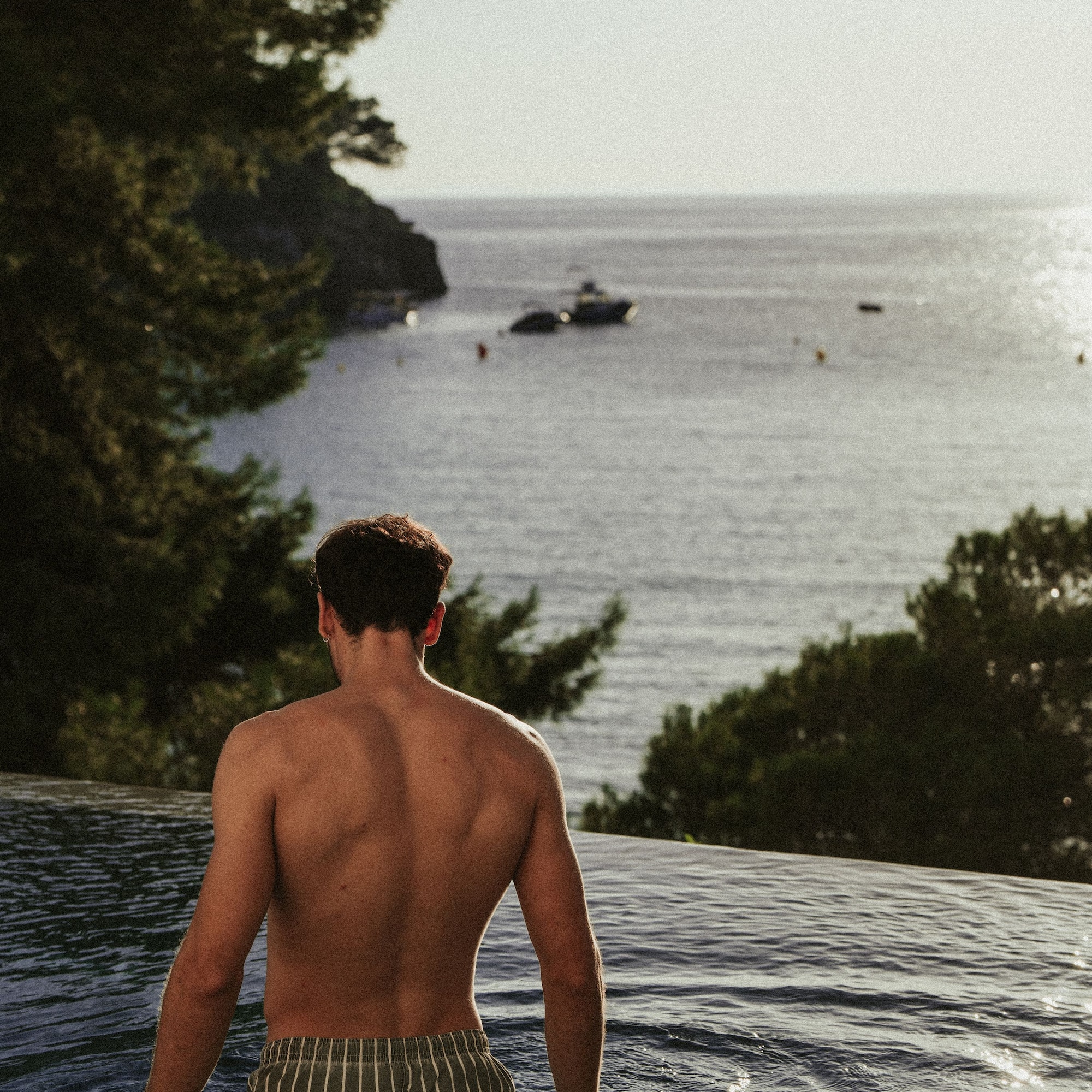 a man sitting in a pool looking out over water