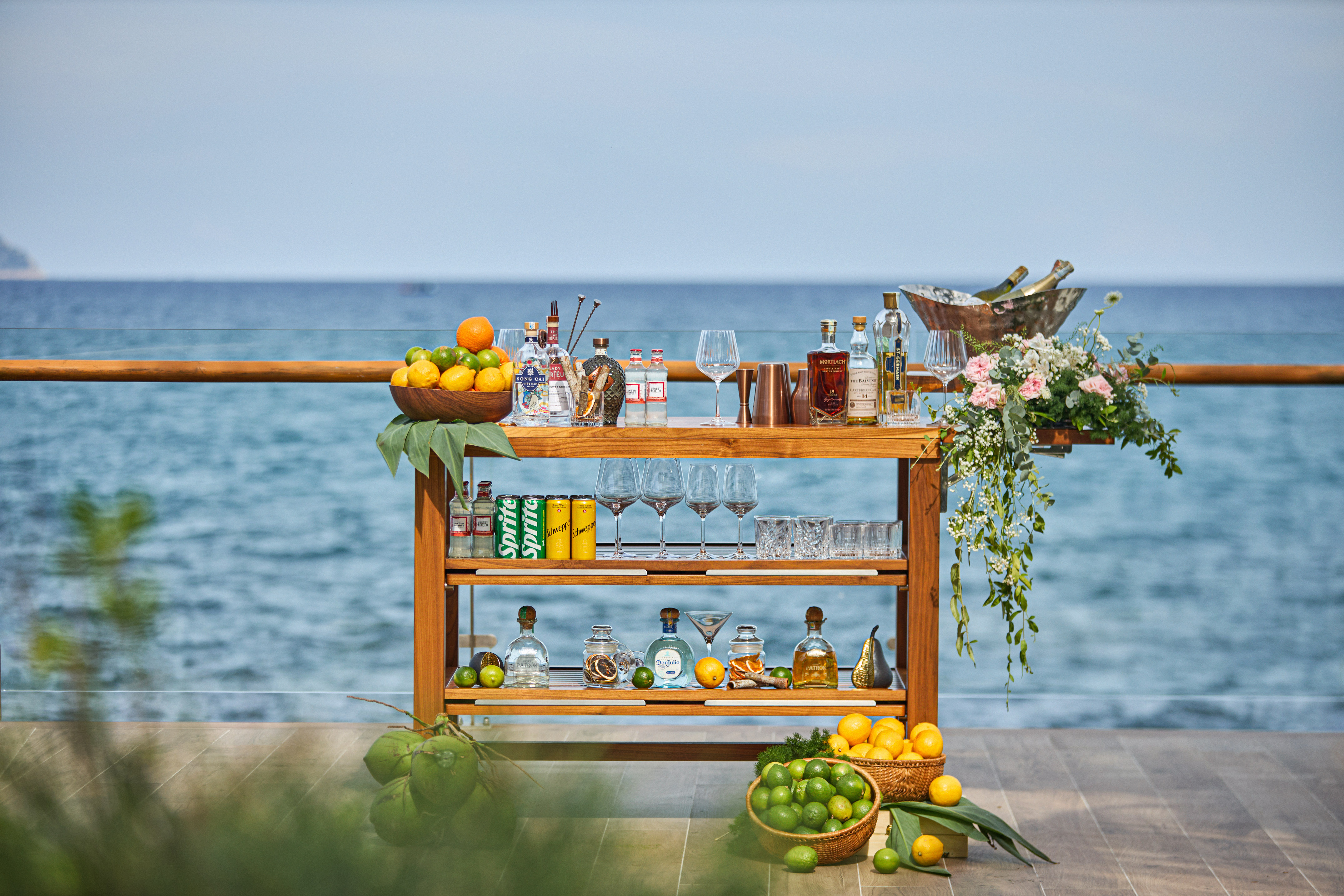 Outdoor cocktail bar with fresh fruit, spirits, and ocean view.