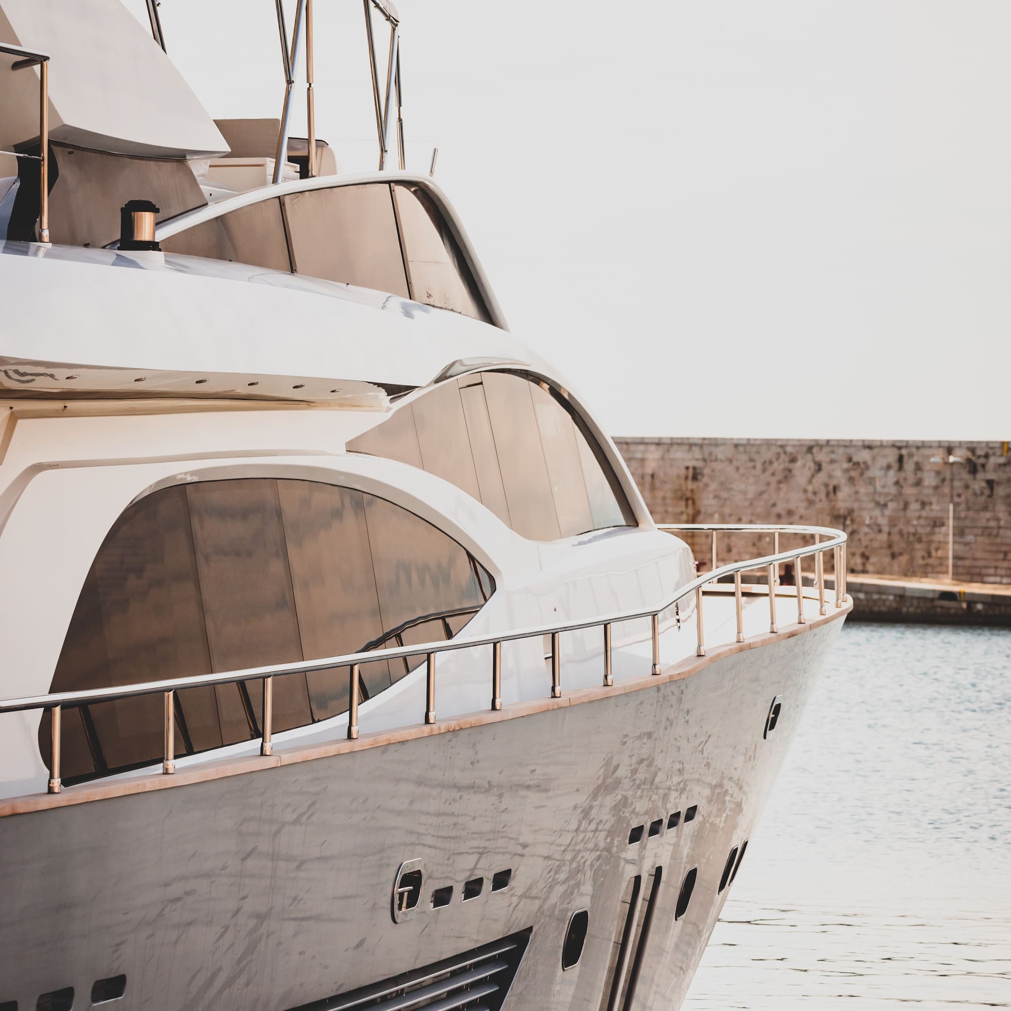 Modern white luxury yacht with sleek design docked at a marina.
