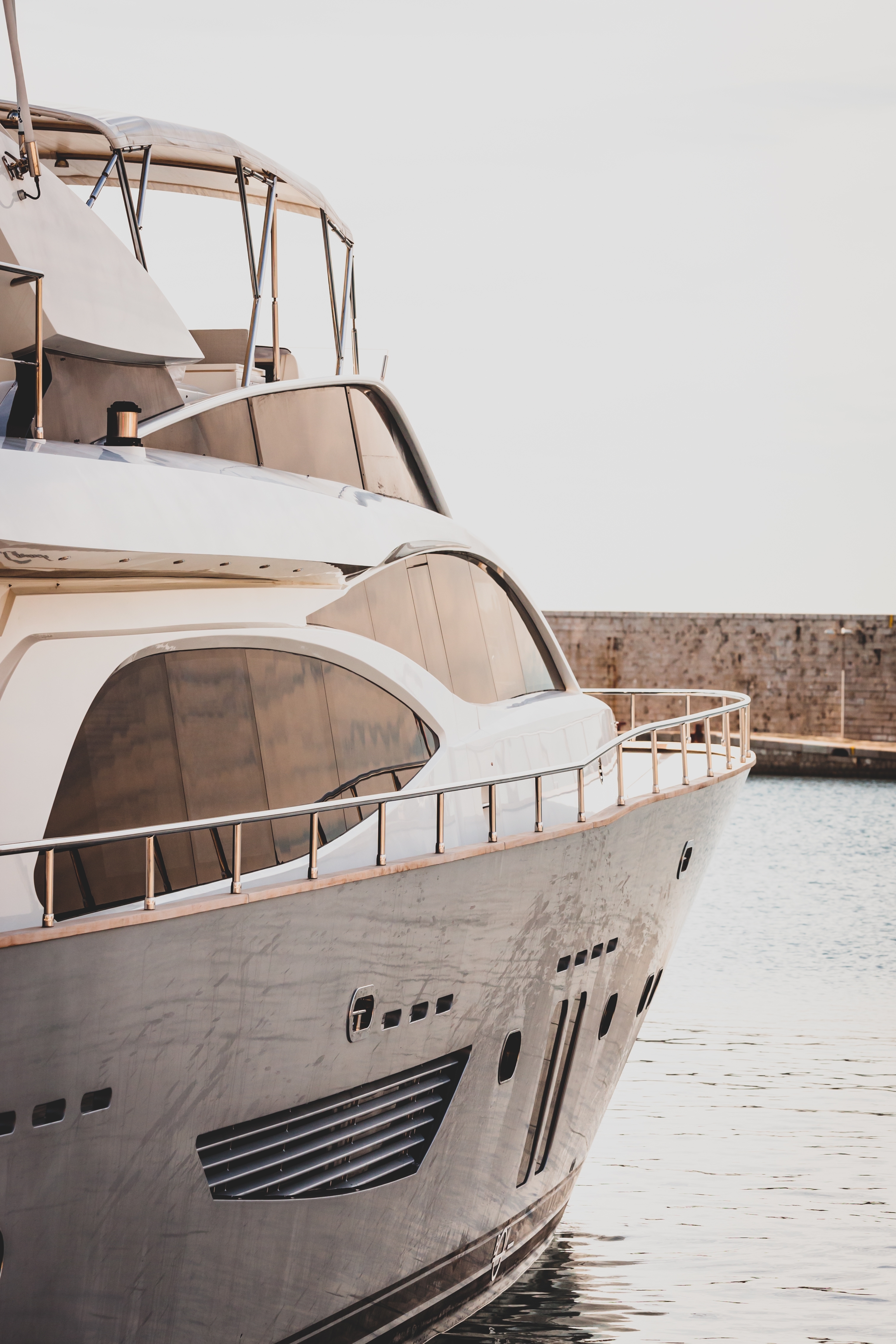Modern white luxury yacht with sleek design docked at a marina.