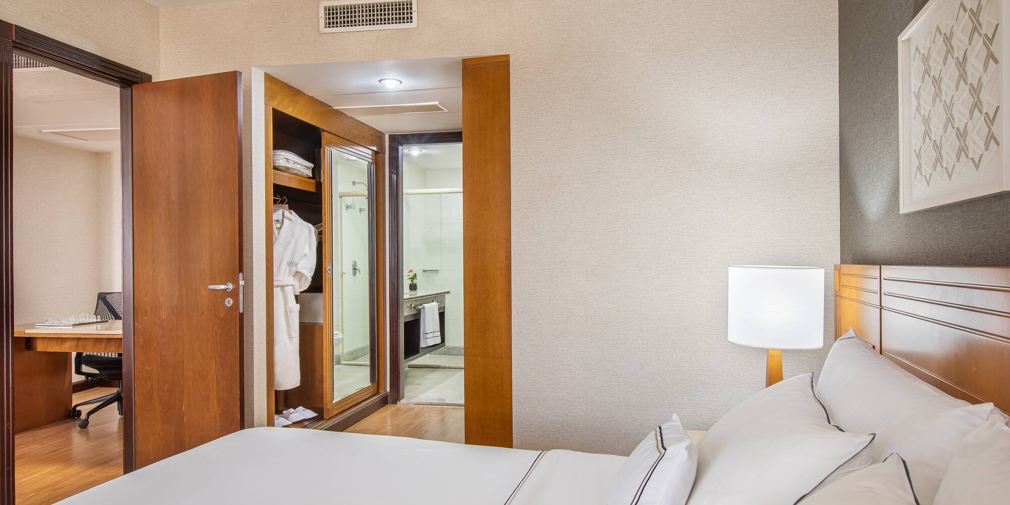 a bed with white sheets and a white lamp in a room