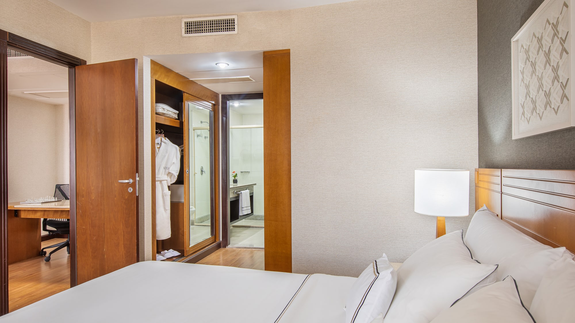 a bed with white sheets and a white lamp in a room