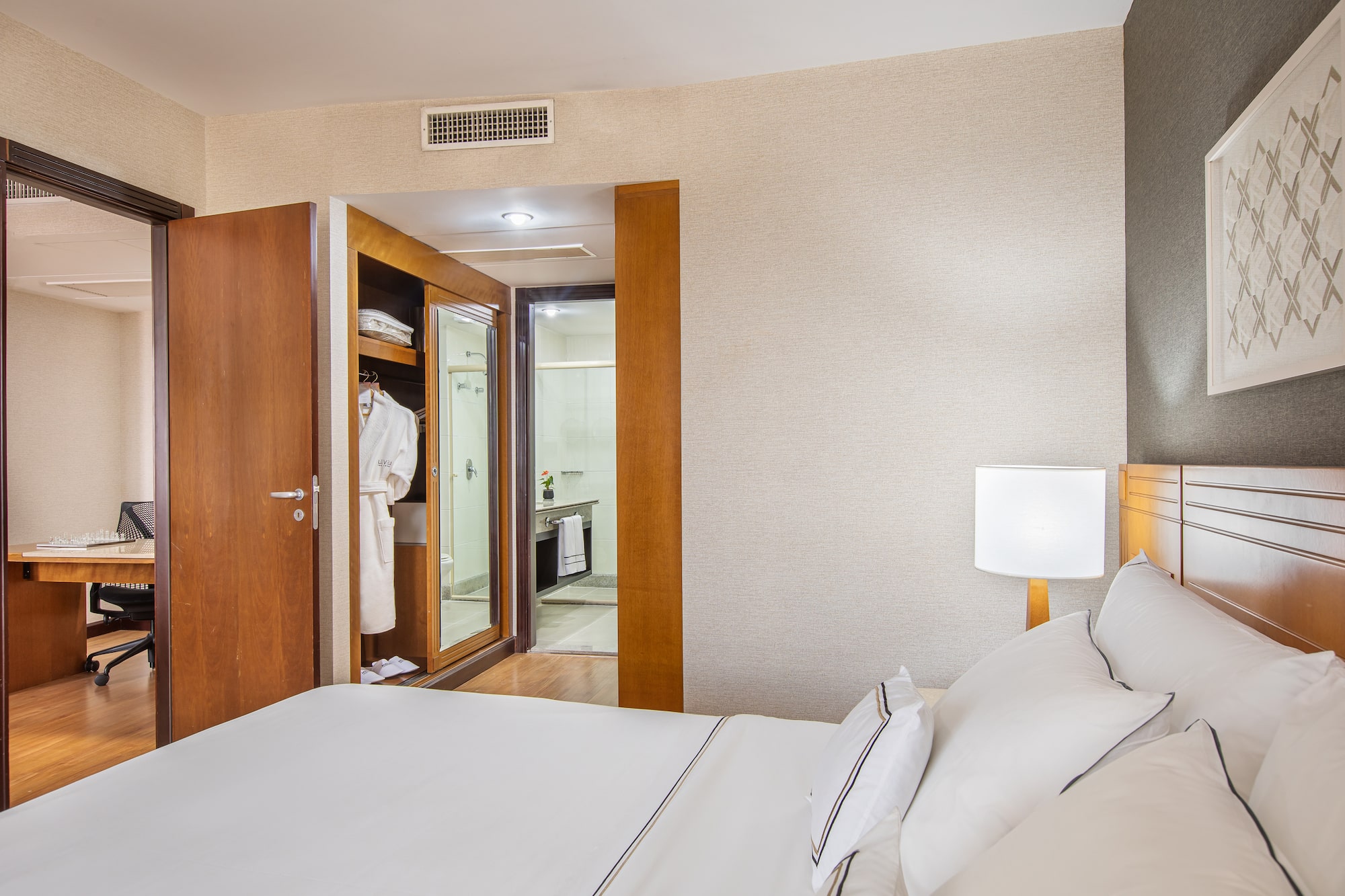 a bed with white sheets and a white lamp in a room