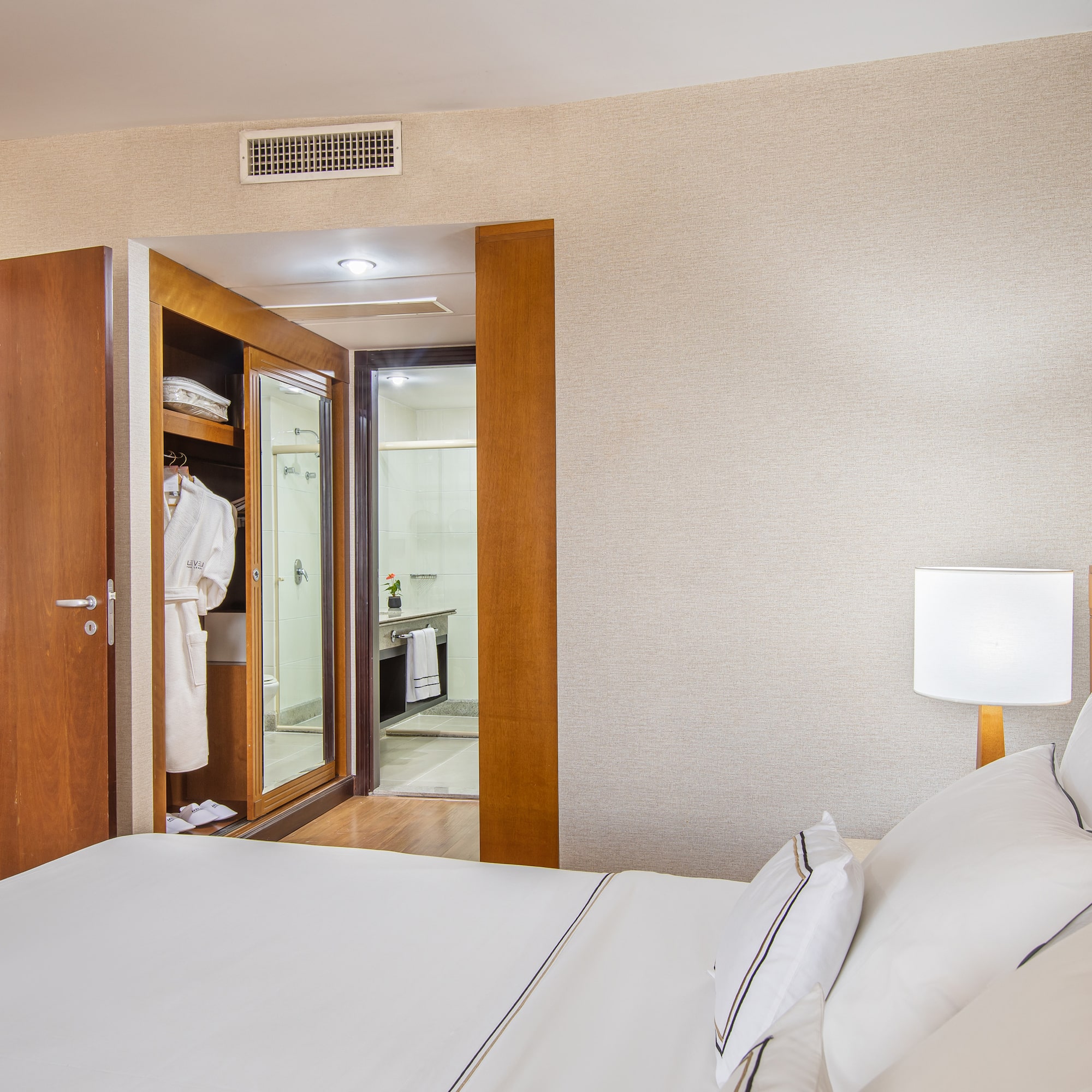 a bed with white sheets and a white lamp in a room