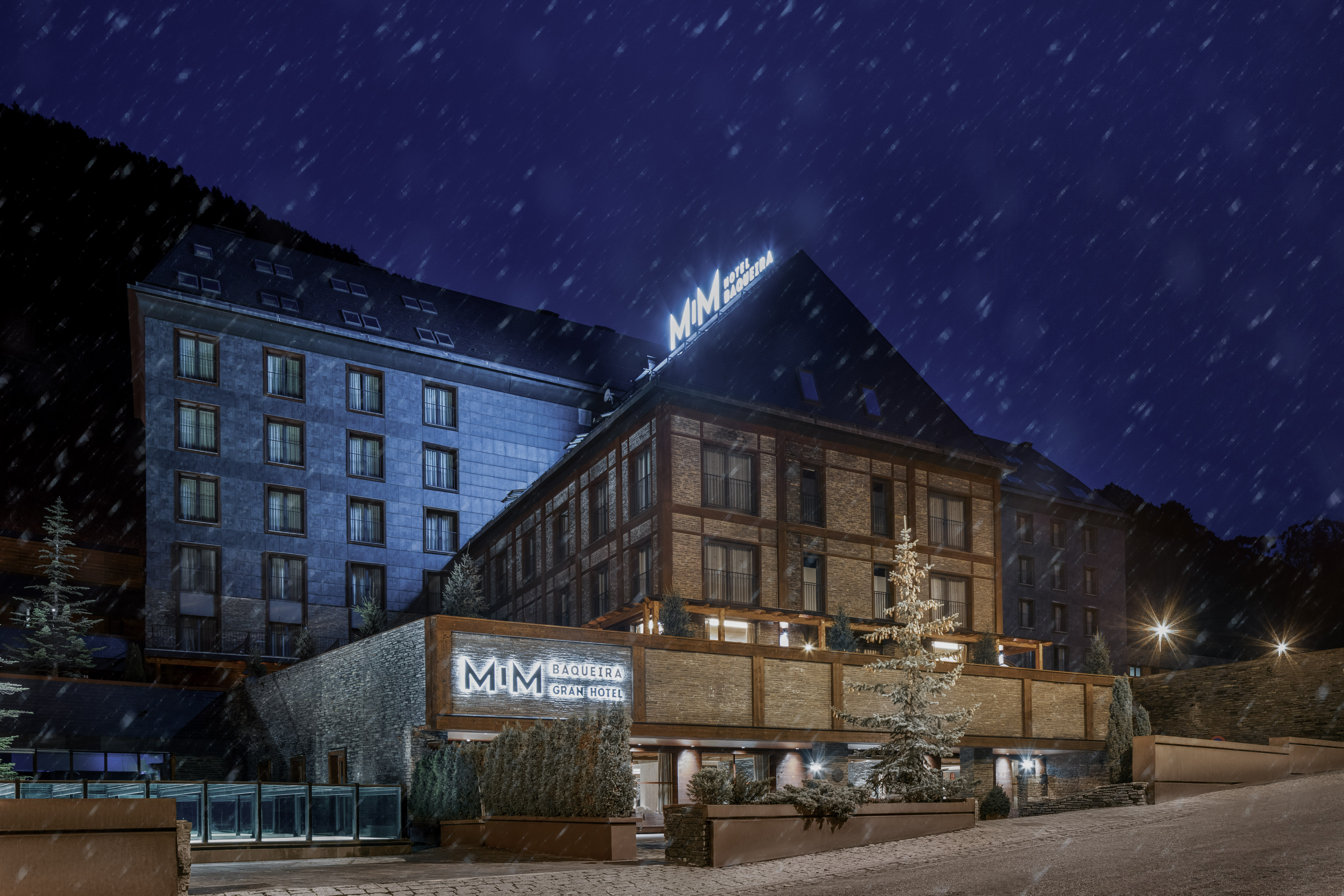 MIM Baqueira Gran Hotel at night during a snowfall, a luxury mountain resort.