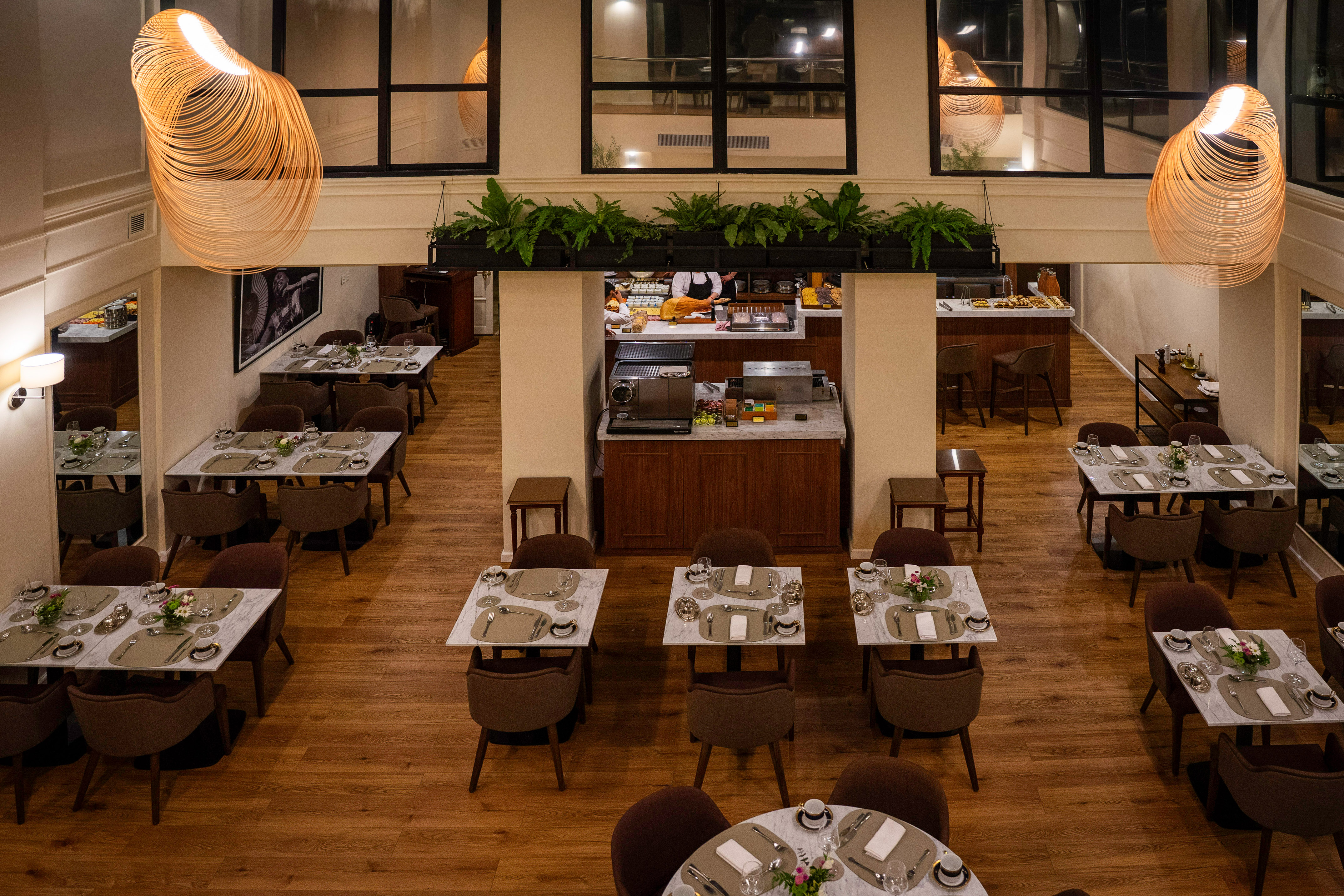 Modern hotel restaurant with set tables, buffet, and unique pendant lighting.