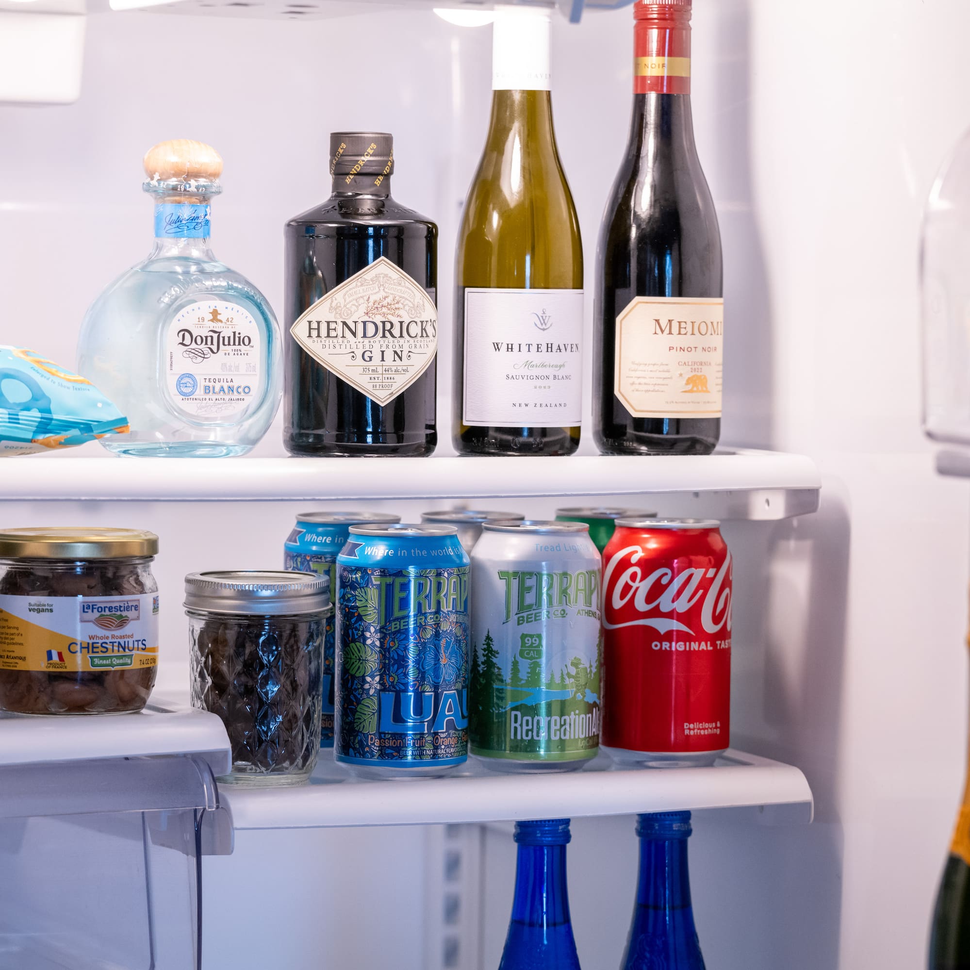 a refrigerator with bottles of alcohol and cans of soda