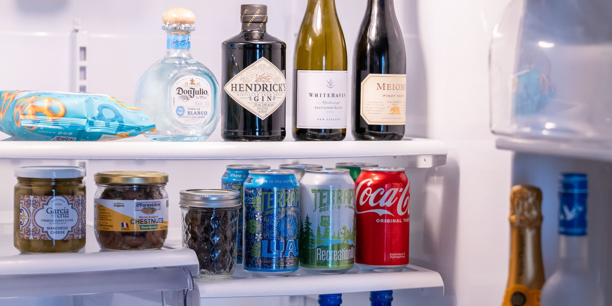 a refrigerator with bottles of alcohol and cans of soda