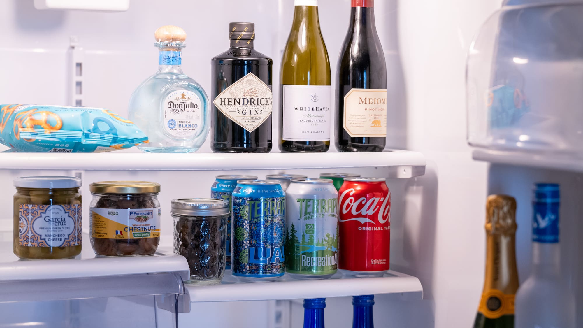 a refrigerator with bottles of alcohol and cans of soda