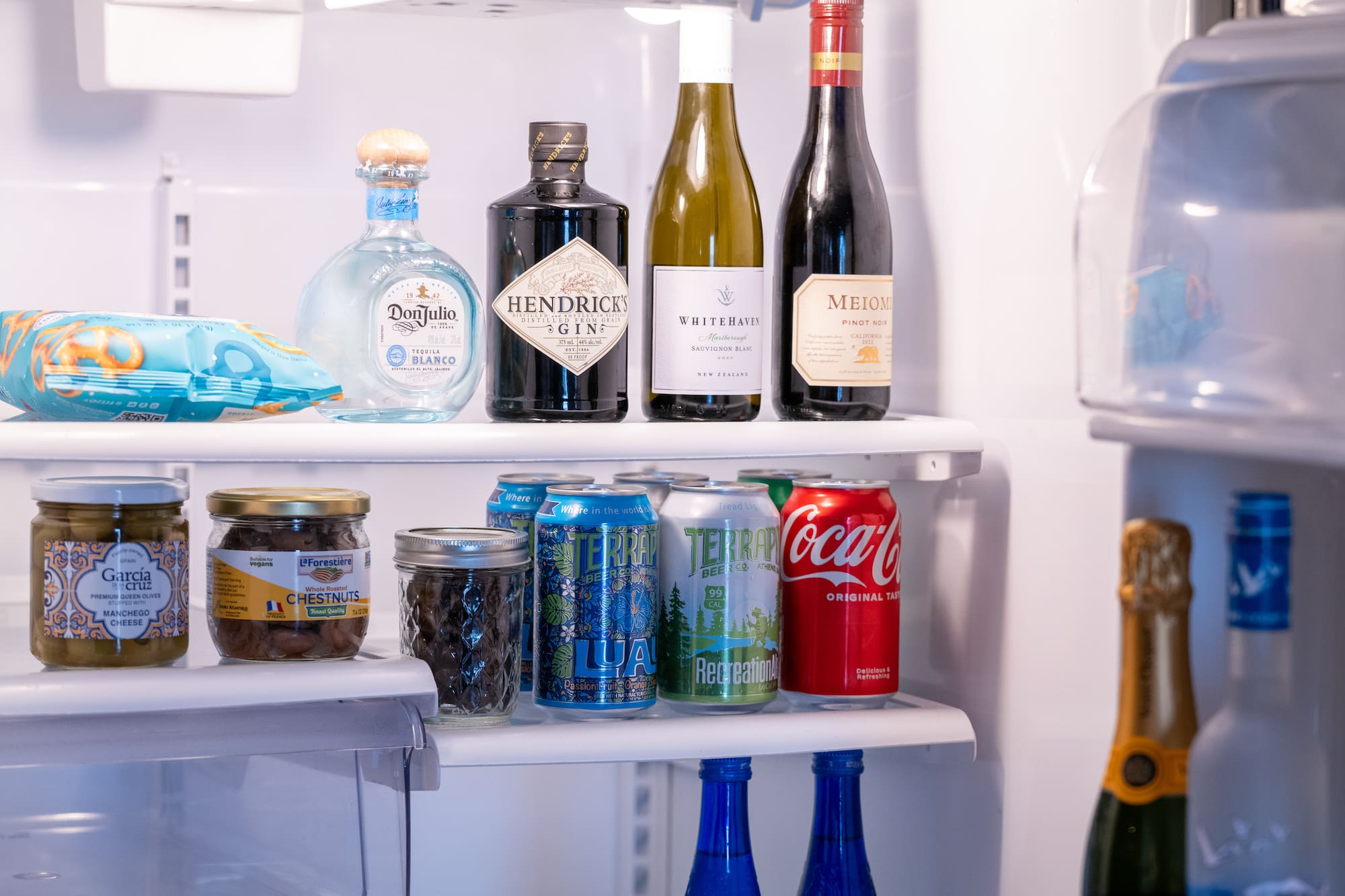 a refrigerator with bottles of alcohol and cans of soda