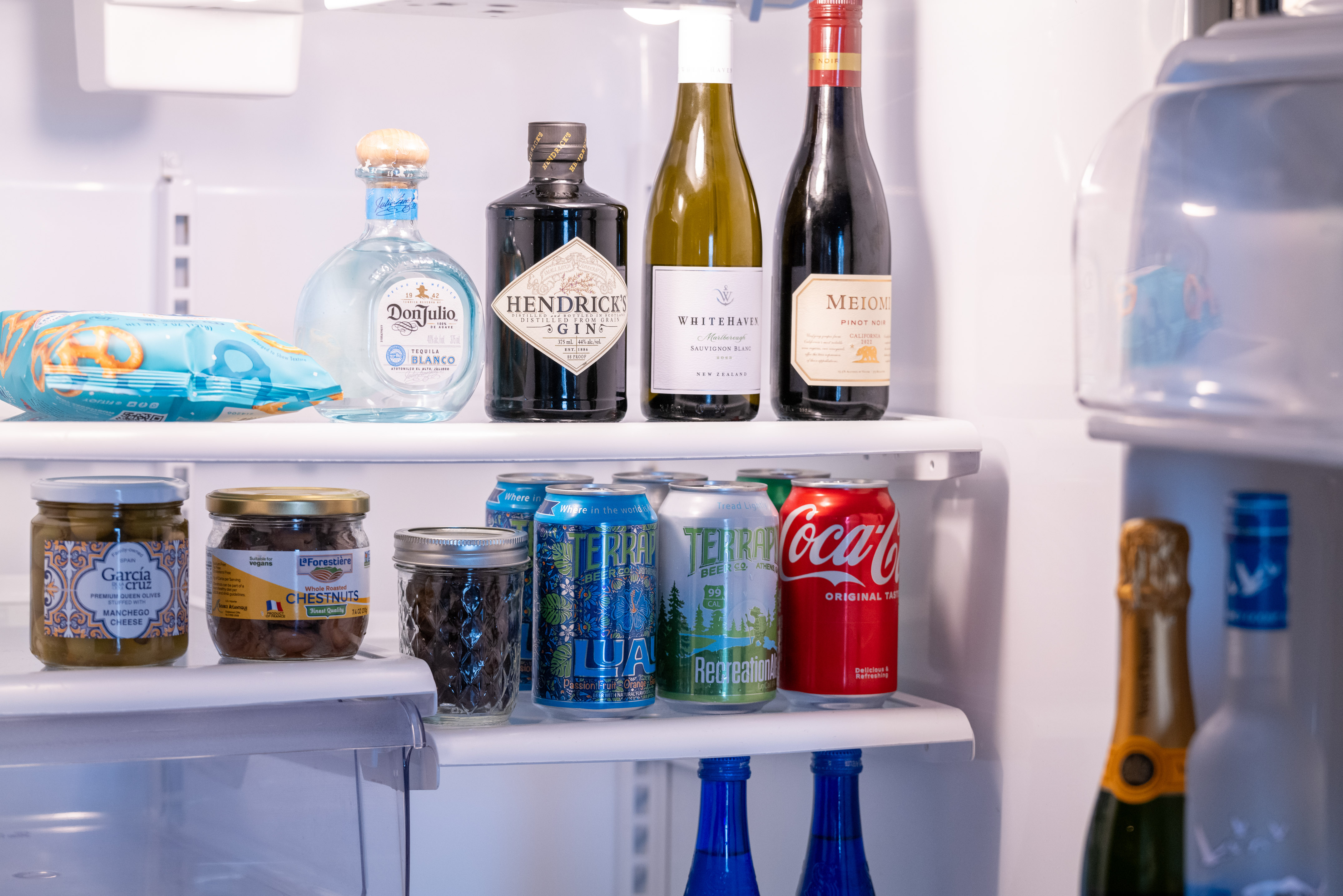 a refrigerator with bottles of alcohol and cans of soda